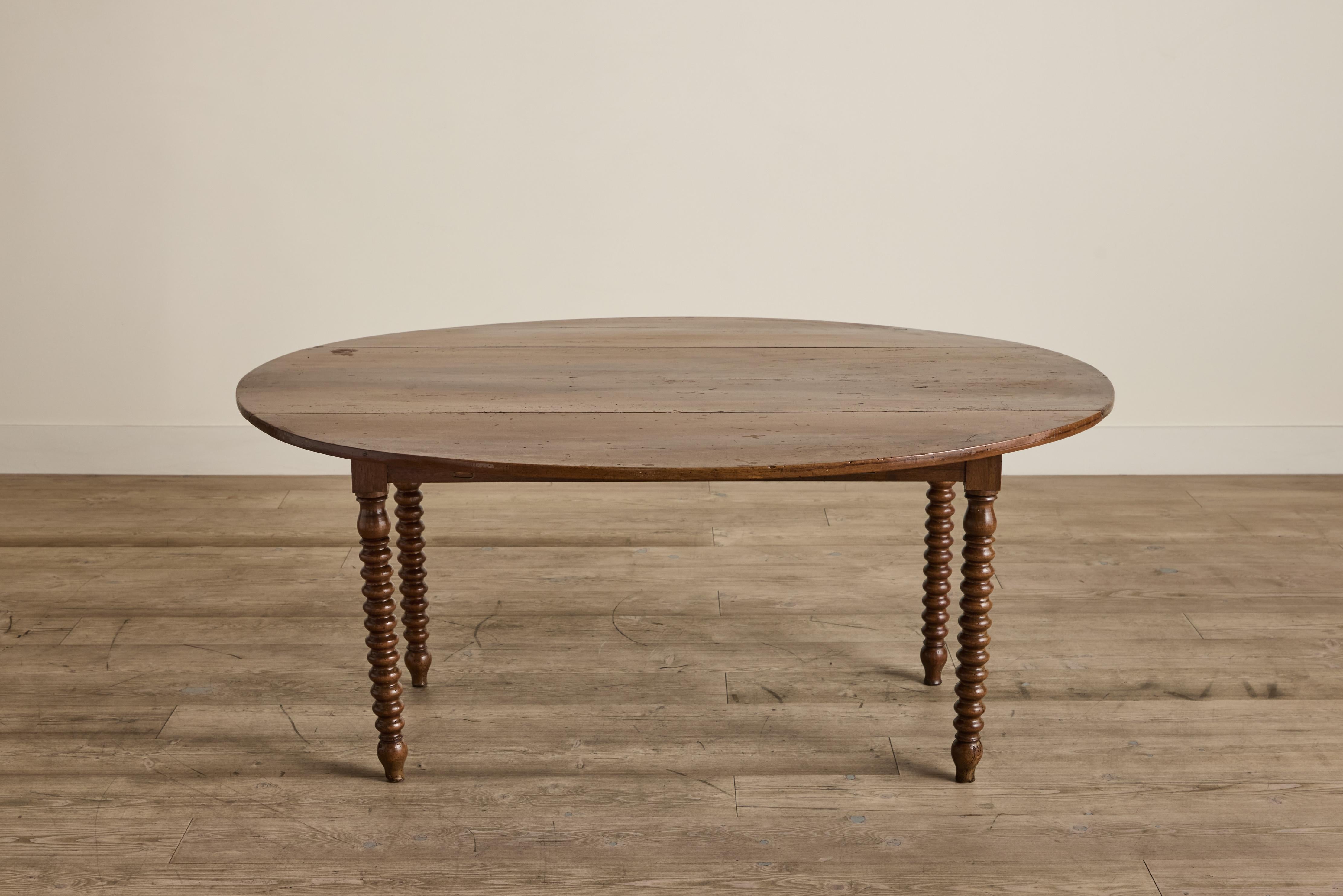 19th century bobbin leg dining table from France. Sides fold down by adjusting wooden slats located in the apron. Table is in good condition with some visible wear that is consistent with age and use. 
