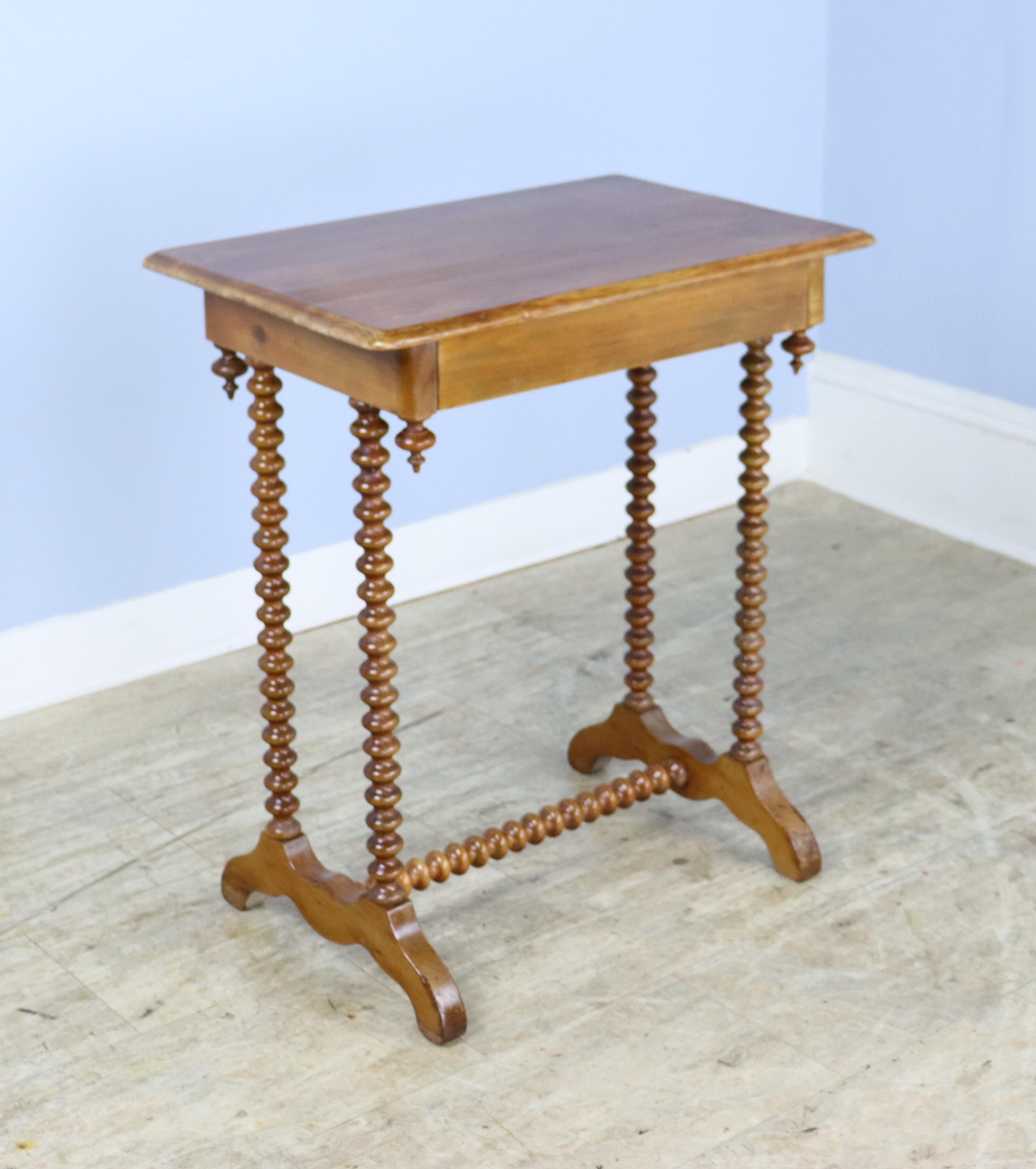A whimsical side, lamp, or occasional table with bobbin legs and support.  Small hidden front drawer.  There is some light distress on the finish, shown in thumbnails.