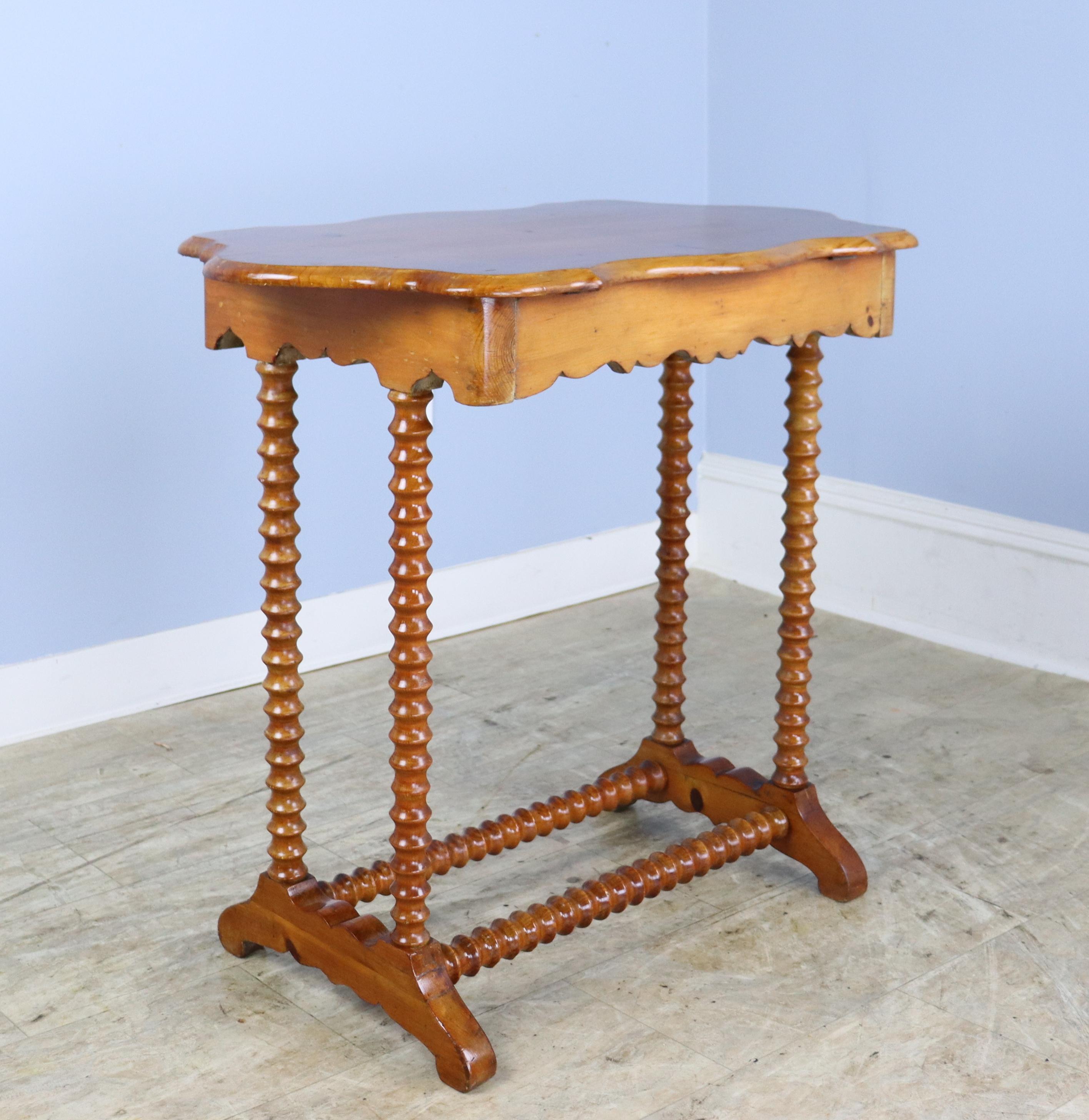 A charming bobbin legged side table with a trestle base and whisically shaped top.  The piece is in good antique condition with some light scratches.