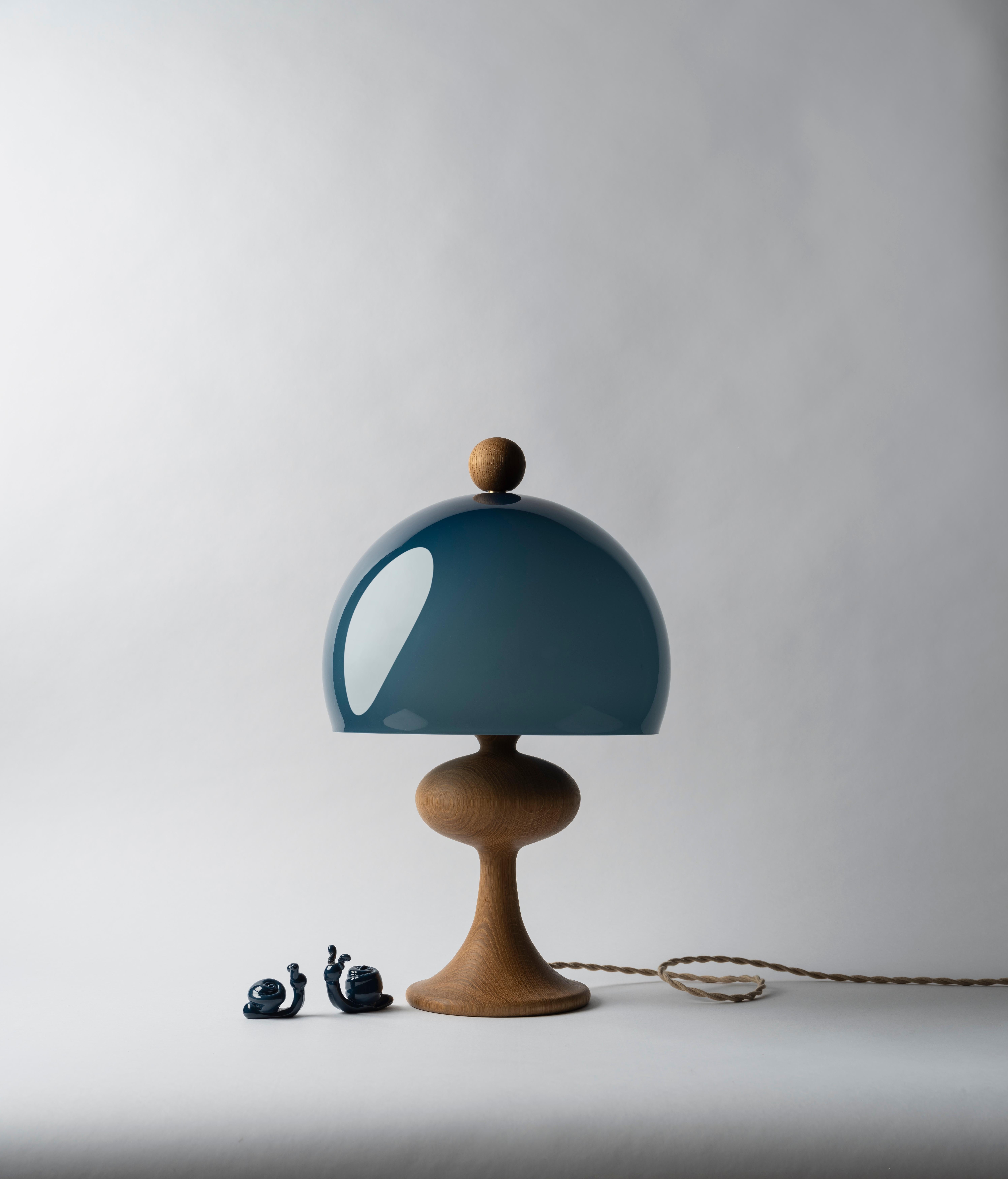 Named after traditional turned-wood bobbin lamps—but a little fancier—Bobine is a playful, pretty table lamp available with either a wood or glass base and a glass shade.  The finial sits on the shade like a pompom on a beanie cap and is matched to