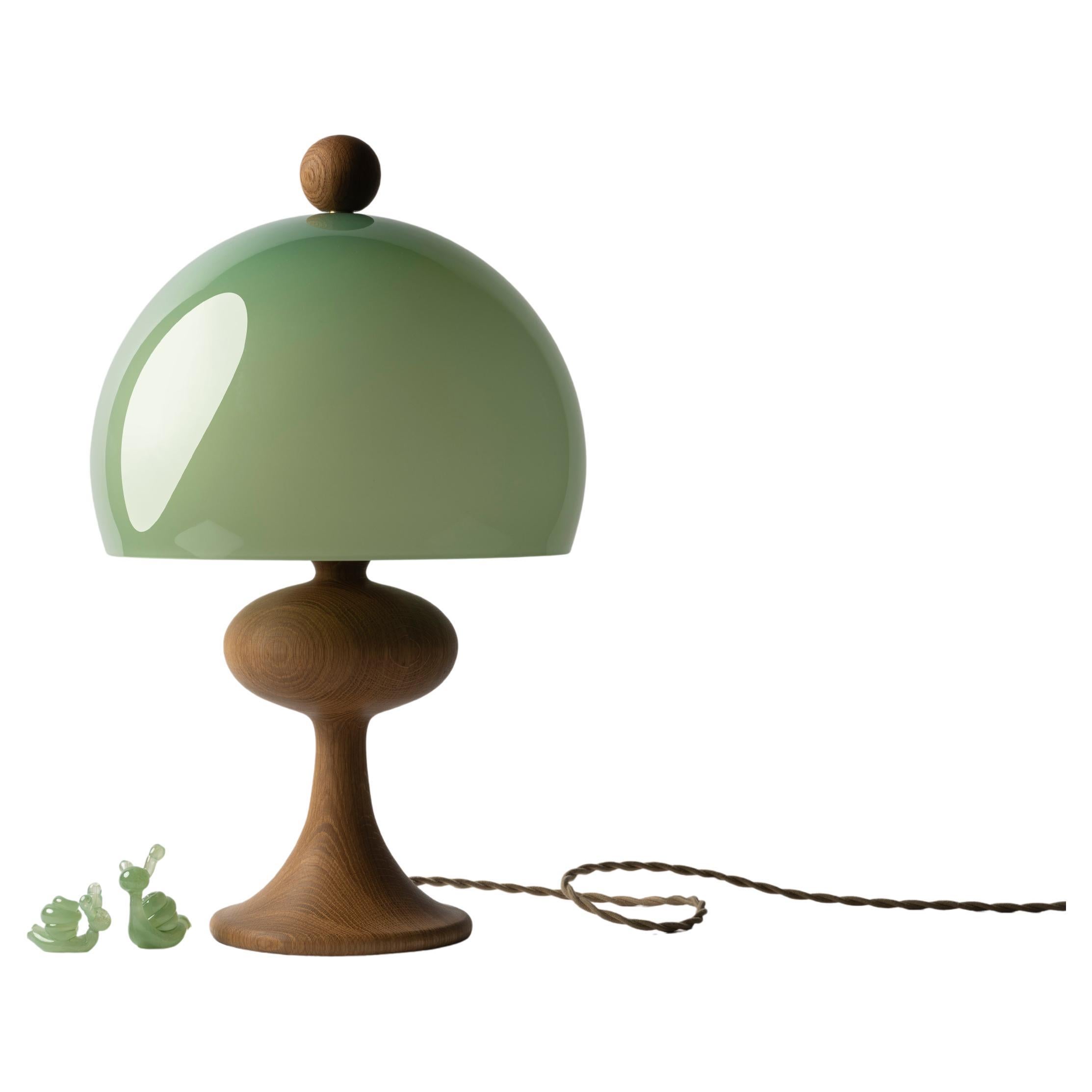 Named after traditional turned-wood bobbin lamps—but a little fancier—Bobine is a playful, pretty table lamp available with either a wood or glass base and a glass shade.  The finial sits on the shade like a pompom on a beanie cap and is matched to