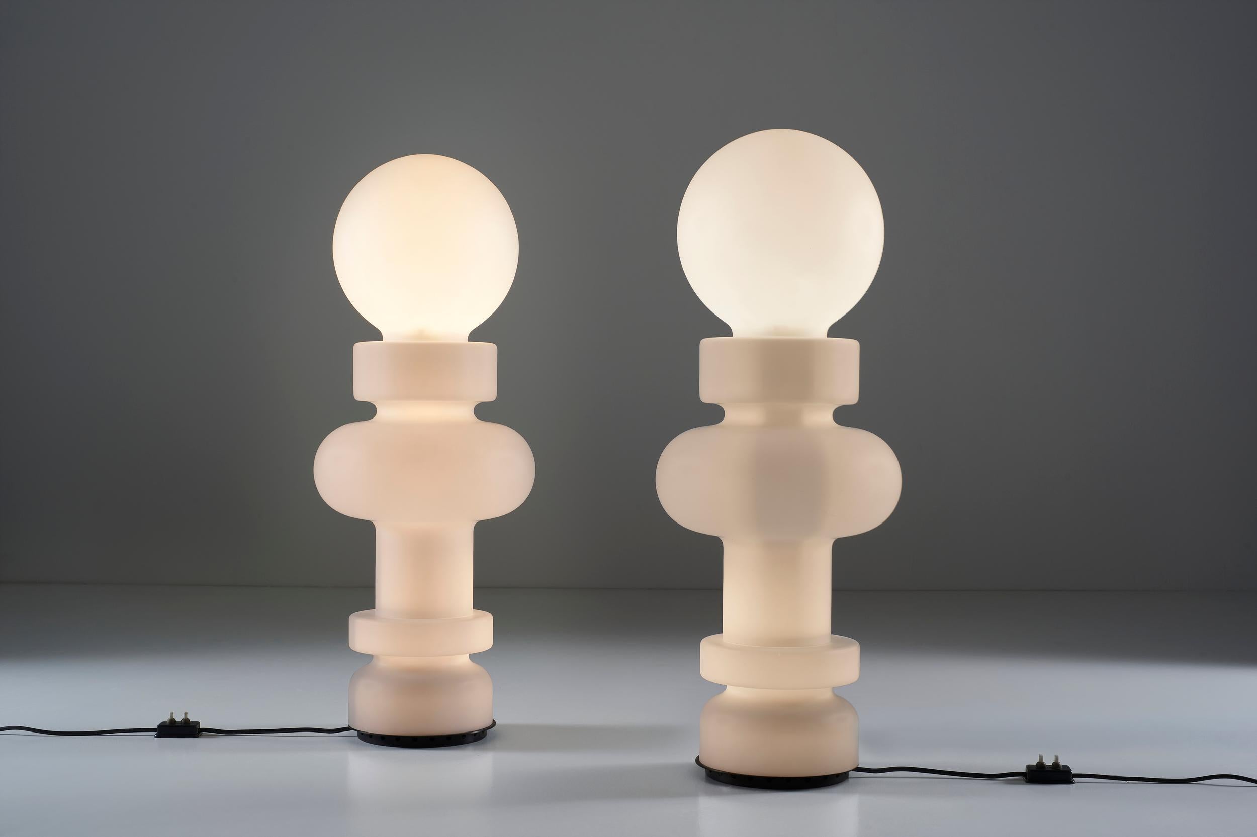 La lampada Re (king) Mod. 2490 di Bobo Piccoli ha un corpo costruito su più livelli. La continuità cilindrica di questo vetro opalino si misura alla base, il fulcro dell'intera struttura. La struttura metallica nasconde un livello di luci