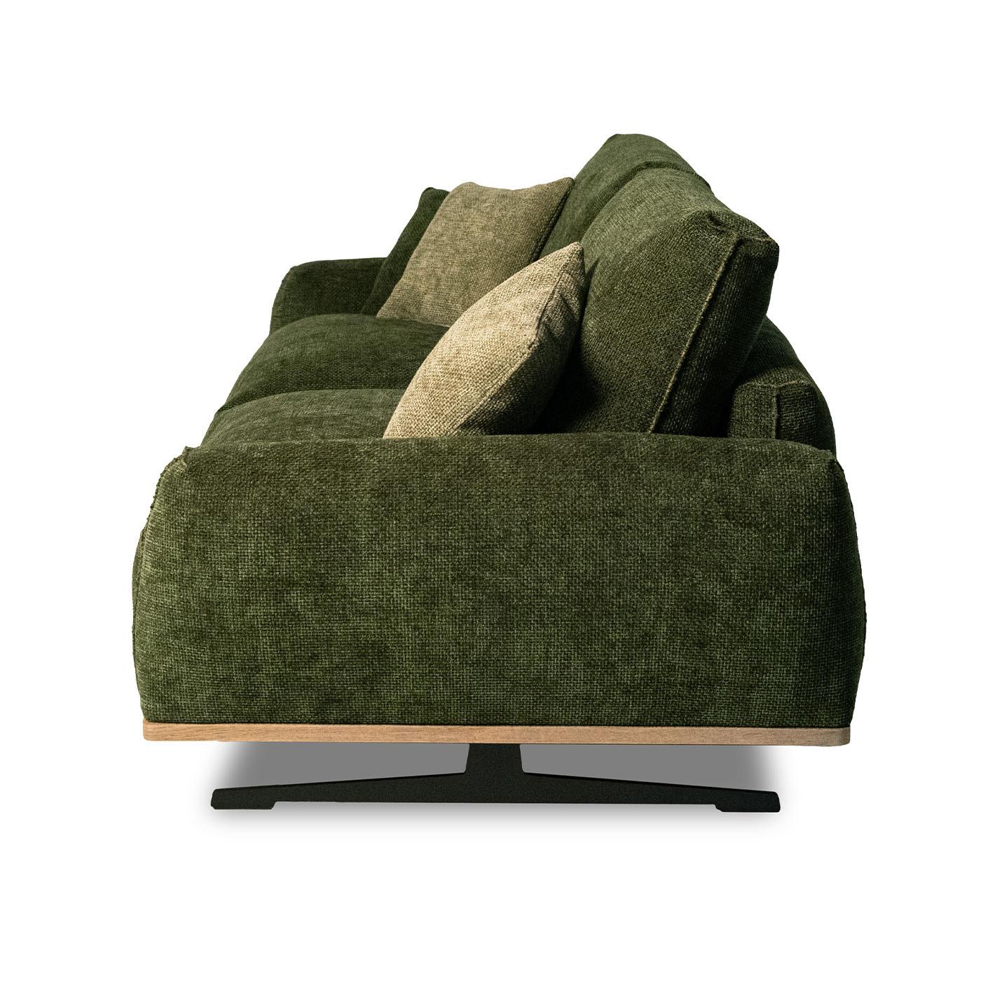 Blending structure and comfort, this sofa features deep green fabric upholstery on a sleek wooden base with slender sled legs. The generously padded seats, filled with high-density polyurethane and goose down, ensure lasting support. Stitching