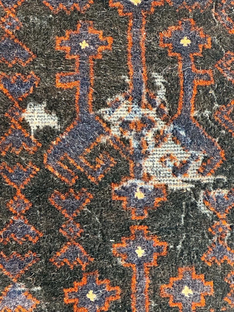Tapis turkmène Baluch du milieu du siècle, avec des motifs tribaux et stylisés, et de jolies couleurs orange et bleu sur fond noir. Quelques usures, quelques manques, dus à l'âge et à l'utilisation. Entièrement noué à la main avec de la laine sur
