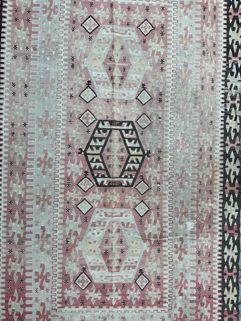 Beautiful mid-century Turkish Kilim featuring intricate geometrical designs and light colors. This antique Anatolian Kilim is finely handwoven with wool, showcasing elegant patterns in shades of  pink, white green and black. Enhance your space with