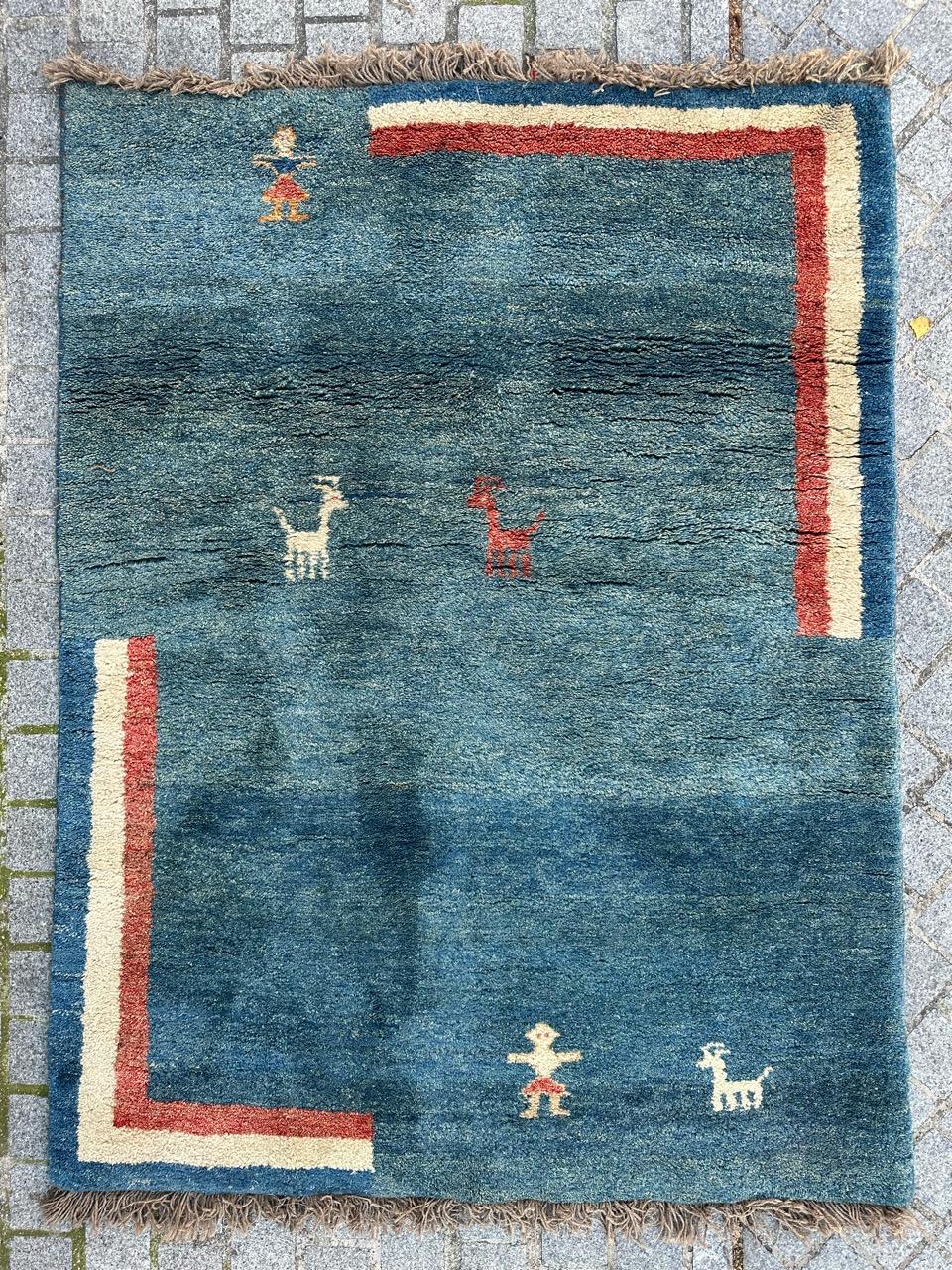 Introducing a stunning Gabbeh rug, meticulously hand-knotted in pure wool on a woolen foundation. This exquisite piece features a tribal-inspired geometric design reminiscent of Art Deco aesthetics. The rich blue field is adorned with intricate red,