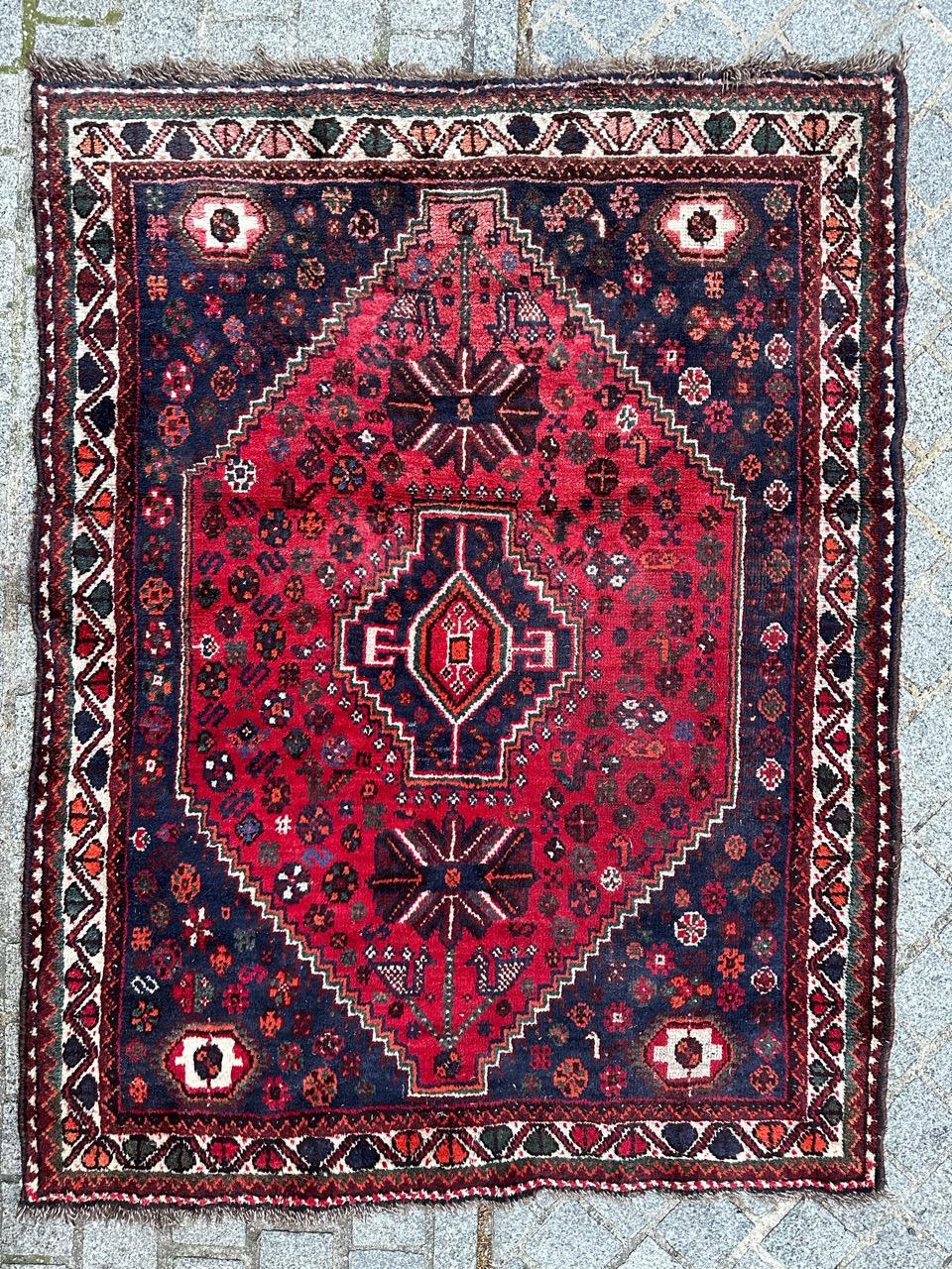 Beautiful vintage Shiraz rug from the second half of the 20th century, entirely hand-knotted in wool on wool. This exquisite piece features intricate geometric and stylized designs in lovely colors.

The field boasts a rich red background adorned