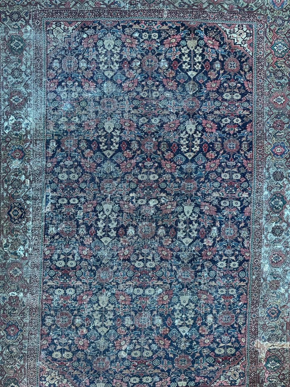 Exquisite late 19th-century distressed Farahan rug featuring a captivating « Herati » design with stylized flowers on a rich navy blue field. Despite some wear and minor damages, this piece is a testament to meticulous craftsmanship, entirely