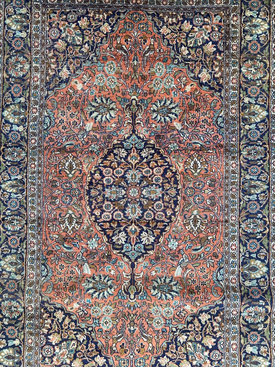 Pretty vintage silk Kashmir rug with beautiful floral design and nice colours with orange field, navy blue, green, yellow, sky blue, brown and white, entirely and finely hand knotted with silk on cotton foundation. 
Uniform wears due to the age and