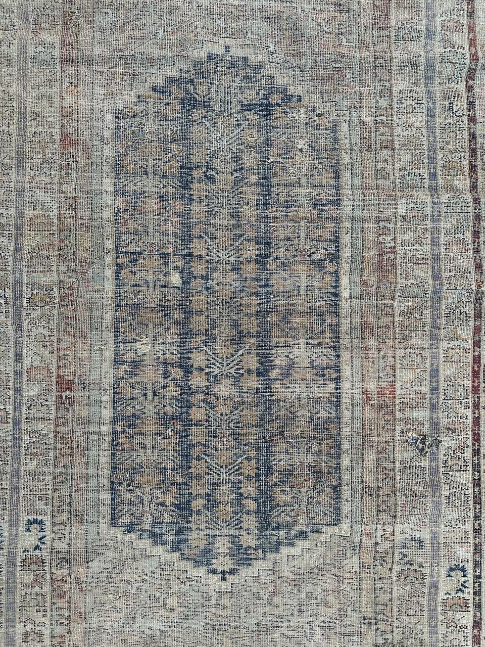 Exquisite distressed 18th-century Turkish Koula antique rug, meticulously handwoven with wool-on-wool craftsmanship. This exceptionally rare piece, though showing signs of age and wear, features a decorative design with stylized flower motifs on a