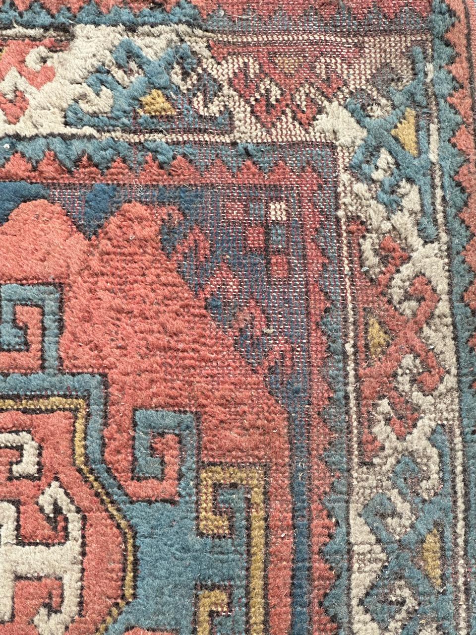 Mid century Turkish rug with beautiful geometrical Kazak style design and nice colours with a pink background, blue, yellow and white, important wears but already in a stable condition, entirely hand knotted with wool on wool foundation