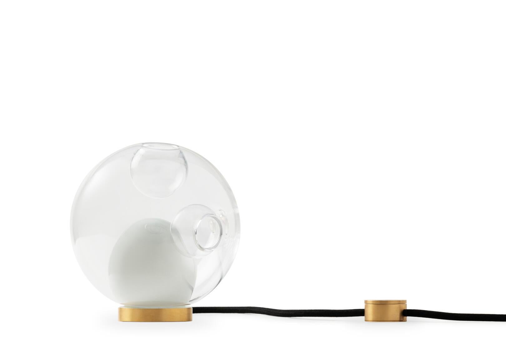 Table lights
A variety of Bocci pendants can be used with the table light hardware, which includes an integral dimming system housed within a sleek brass cylinder. The black fabric cord is semi-rigid and may be sculpted to add form. The brass stand