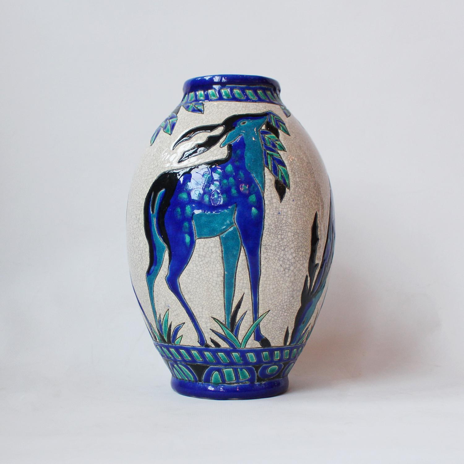 Biches Bleues' an Art Deco, crackle glazed ceramic vase designed by Charles Catteau (1880-1966) for Boch Frères. A tapered vase painted with grazing deer in shades of blue. Numbered to underside.



 