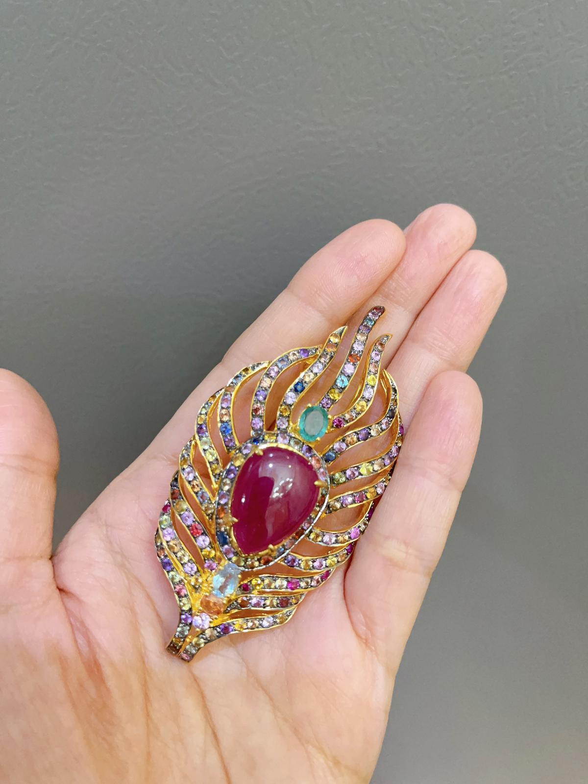 Bochic Multi Natural Gem Brooch 
Natural Ruby, Colors - Red, 12 Carats 
Natural Multi color Sri Lankan sapphires - 9 Carats 
Sapphire colors:
Green, yellow, pink, orange, blue and rose 
Round brilliant 
Natural Green Emerald - 1 Carat 
Oval shape -