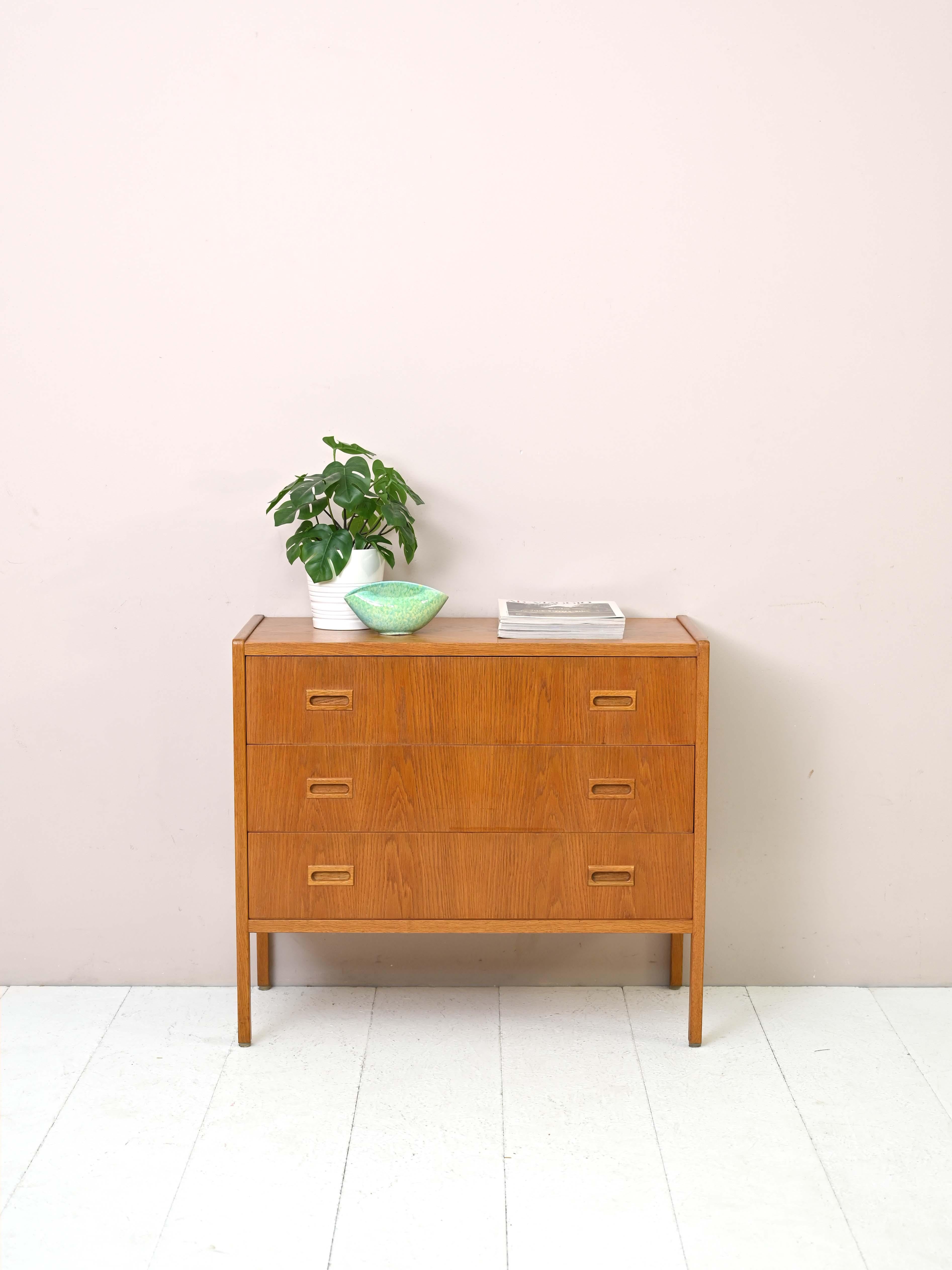 Teak cabinet designed by B.Fridhagen in 1960.
 
This regular, square-shaped chest of drawers is distinguished by the clear oak wood profiles that go into the legs, framing the frame.
Its small size makes it suitable for various rooms in the
