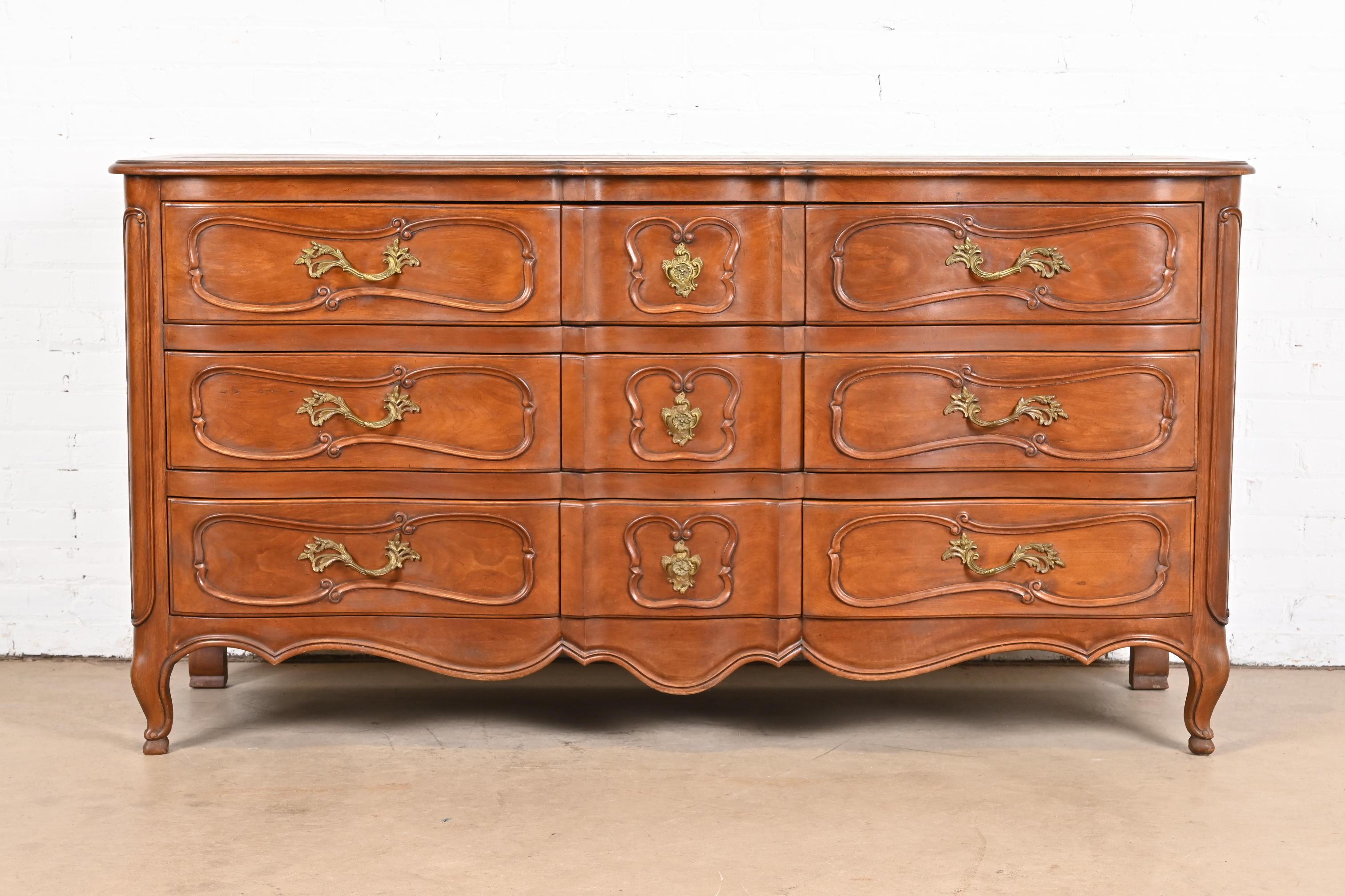A beautiful French Provincial Louis XV style nine-drawer triple dresser or chest of drawers

By Jacques Bodart

USA, Circa 1960s

Carved fruitwood, with original brass hardware.

Measures: 66