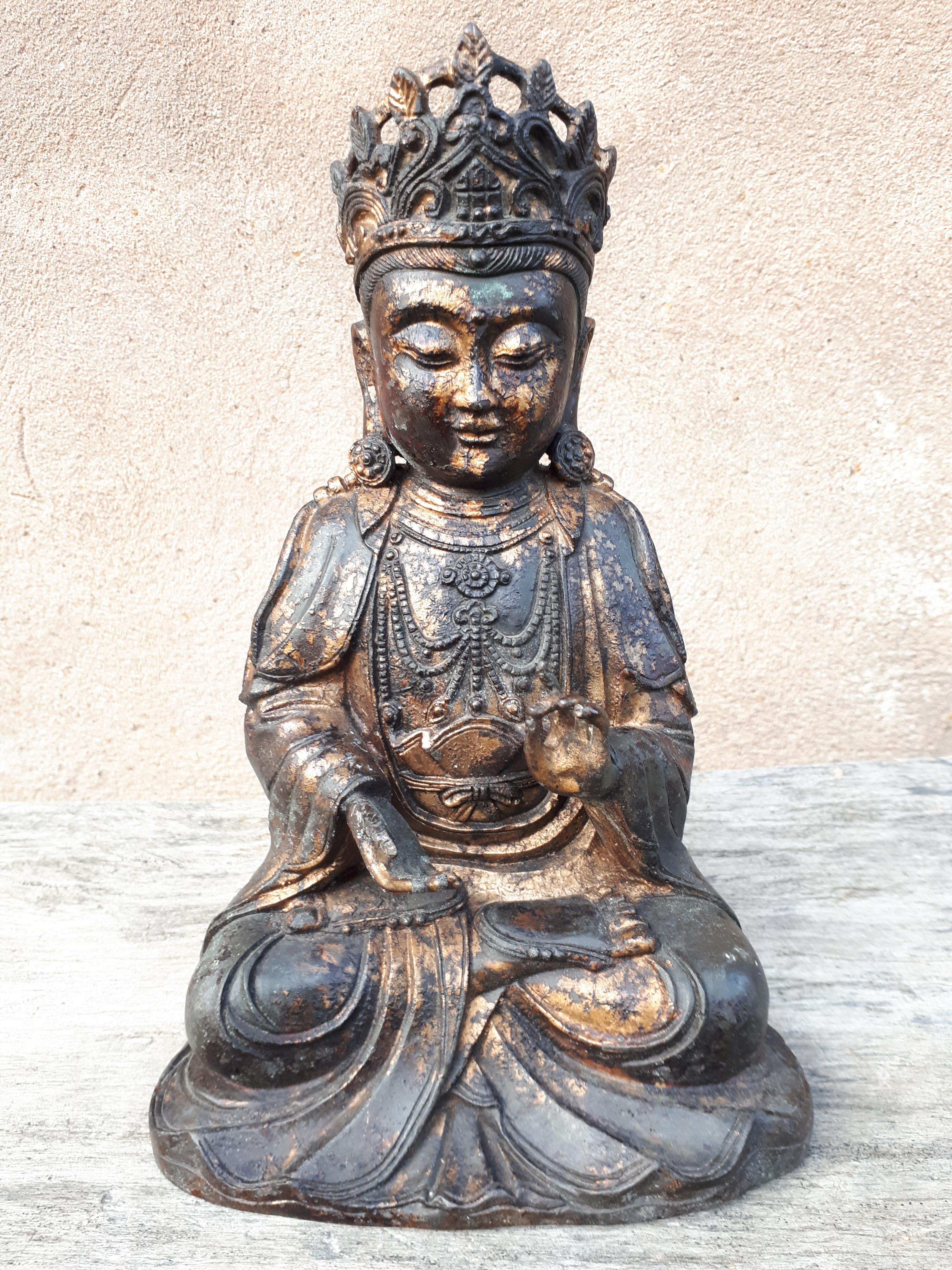 Guanyin en bronze représentée assise, la main gauche en vitarka mudra, vêtue d'une robe ample aux plis volumineux.
Poids : 1.977 kg.