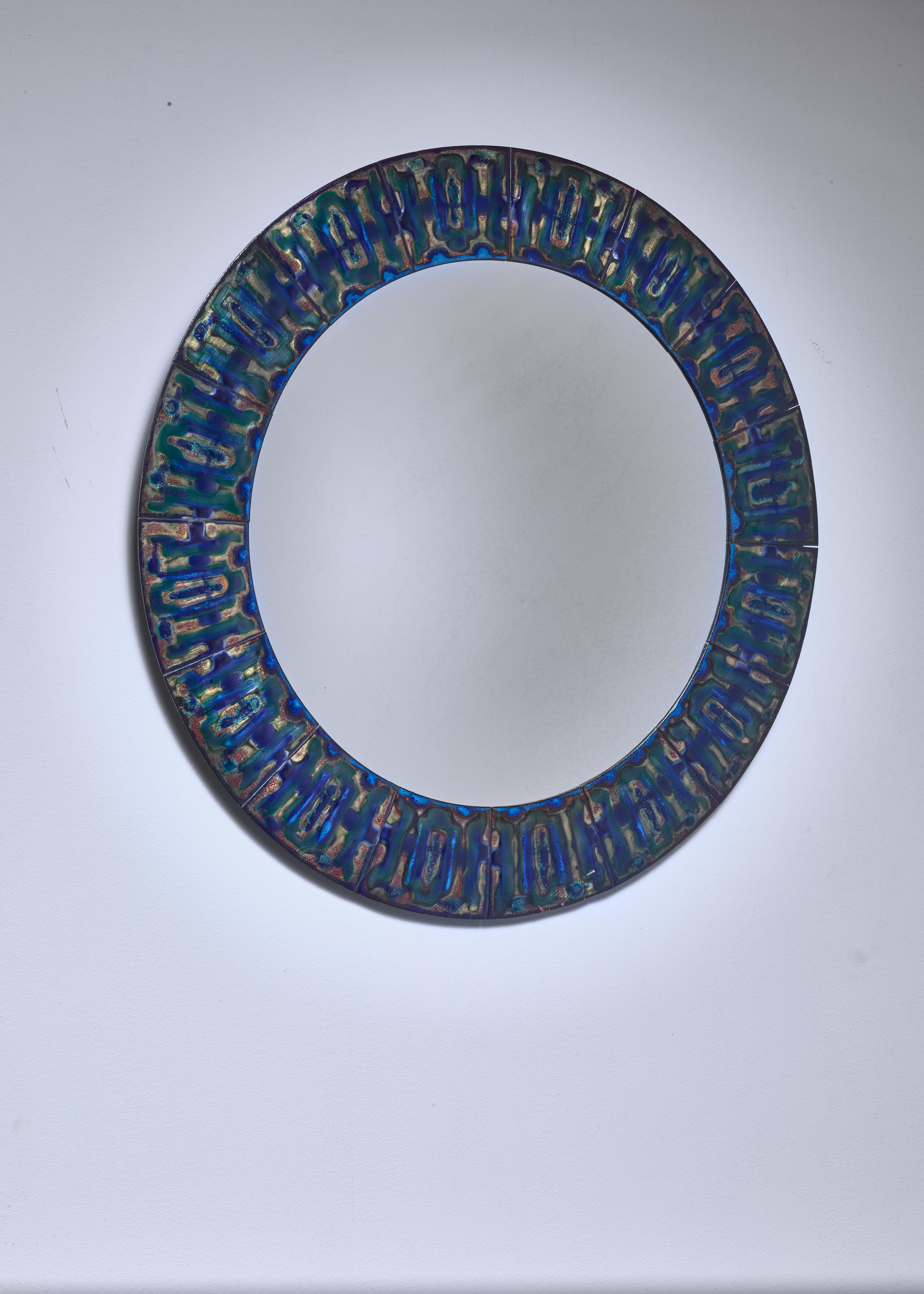 A round wall mirror by Danish designer Bodil Eje (1931-2006). The mirror has a frame made of polychrome enameled copper plates with a beautiful pattern.

Signed on the reverse by the artist.
 