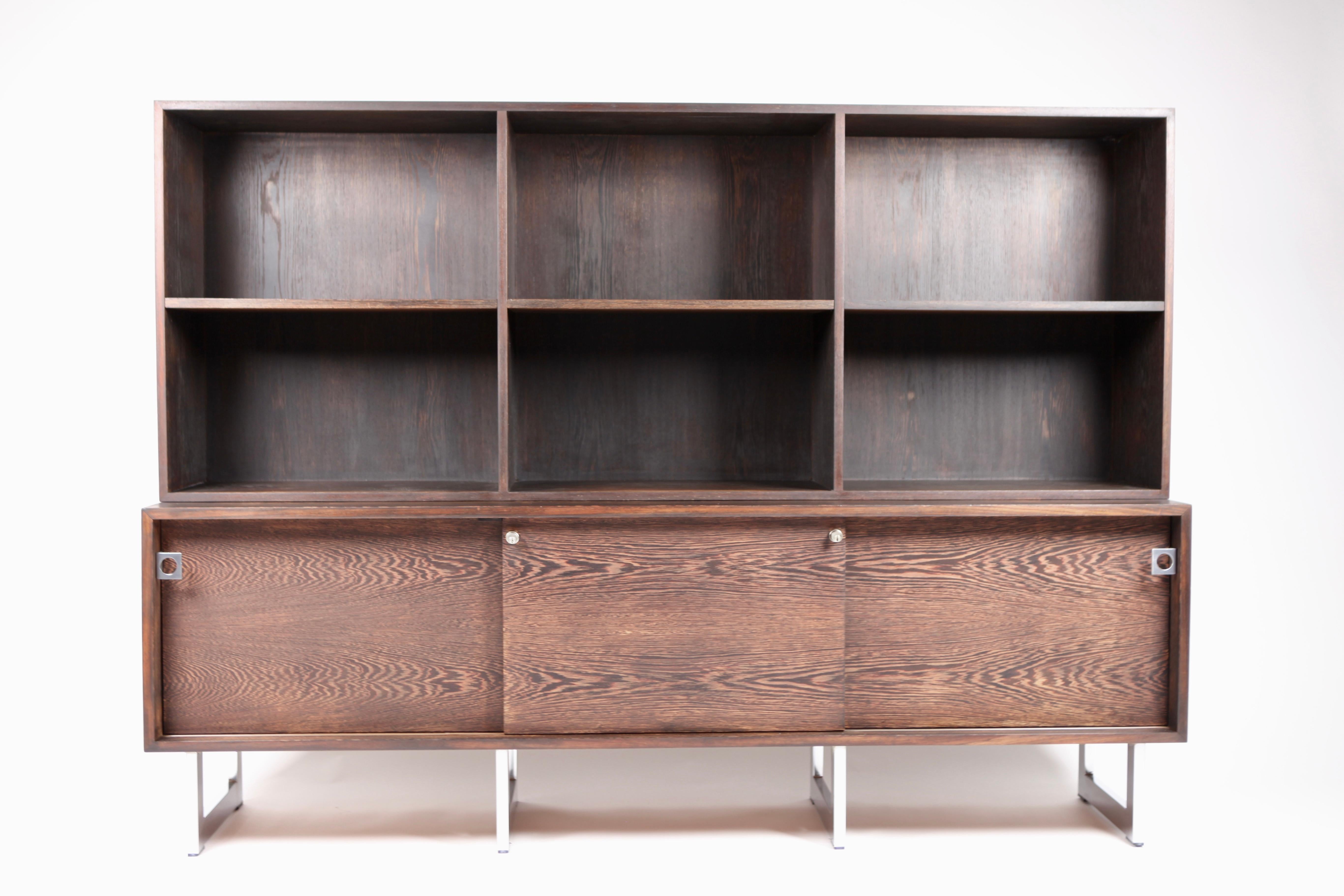 Bodil Kjær, freestanding sideboard with bookshelf in Wenge and chromed steel, executed by E.Pedersen & Son a-s, in the 1960s. Signed with paper label.
The front is divided in 3 sliding doors.
The credenza is freestanding with Wenge