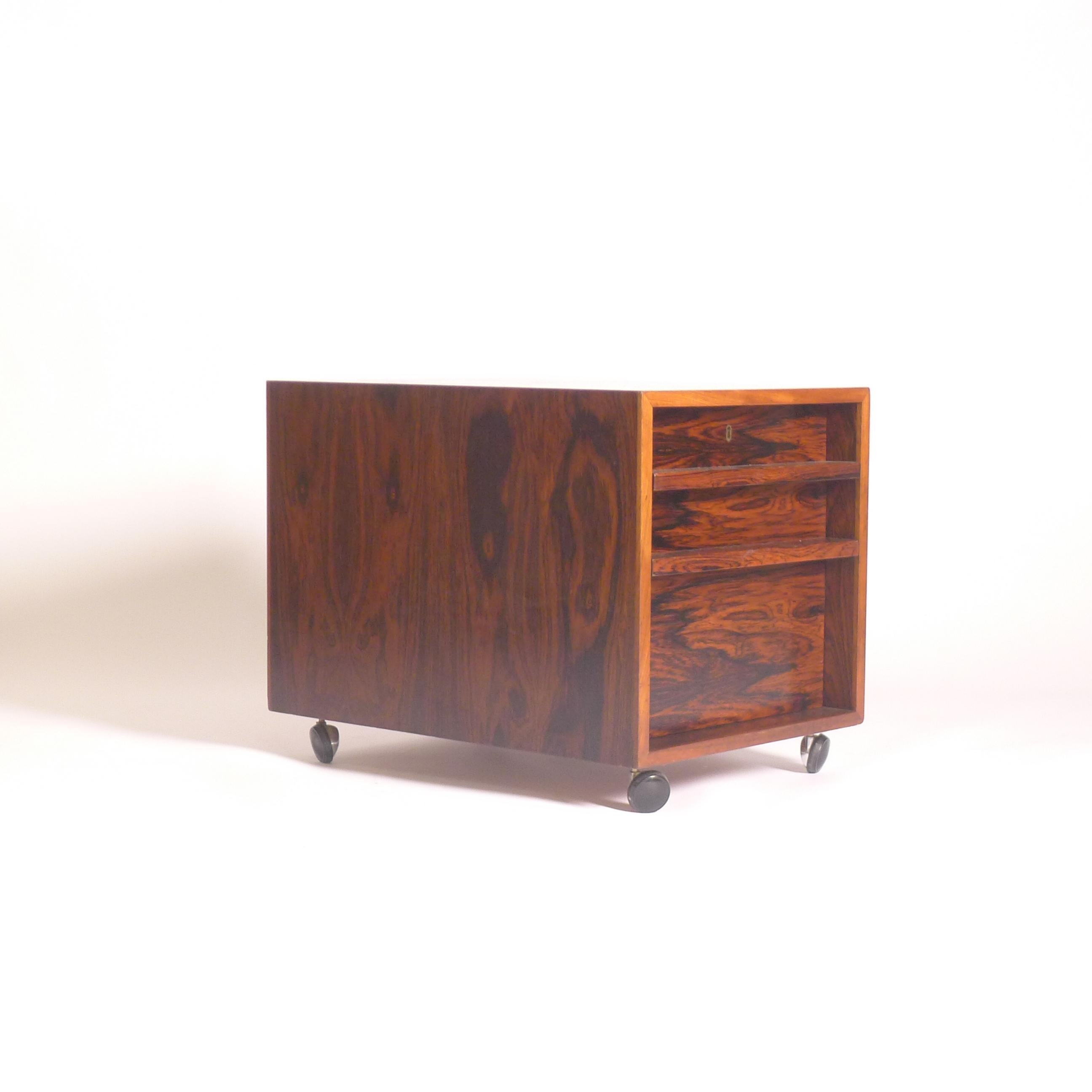 Raro mobiletto su ruote disegnato da Bodil Kjaer nel 1959, prodotto da Pedersen & Son ed edito da Jason Møbler,  Wood Wood, primi anni '50, in legno impiallacciato di palissandro dalle bellissime venature.

Comprende due cassetti bassi e uno