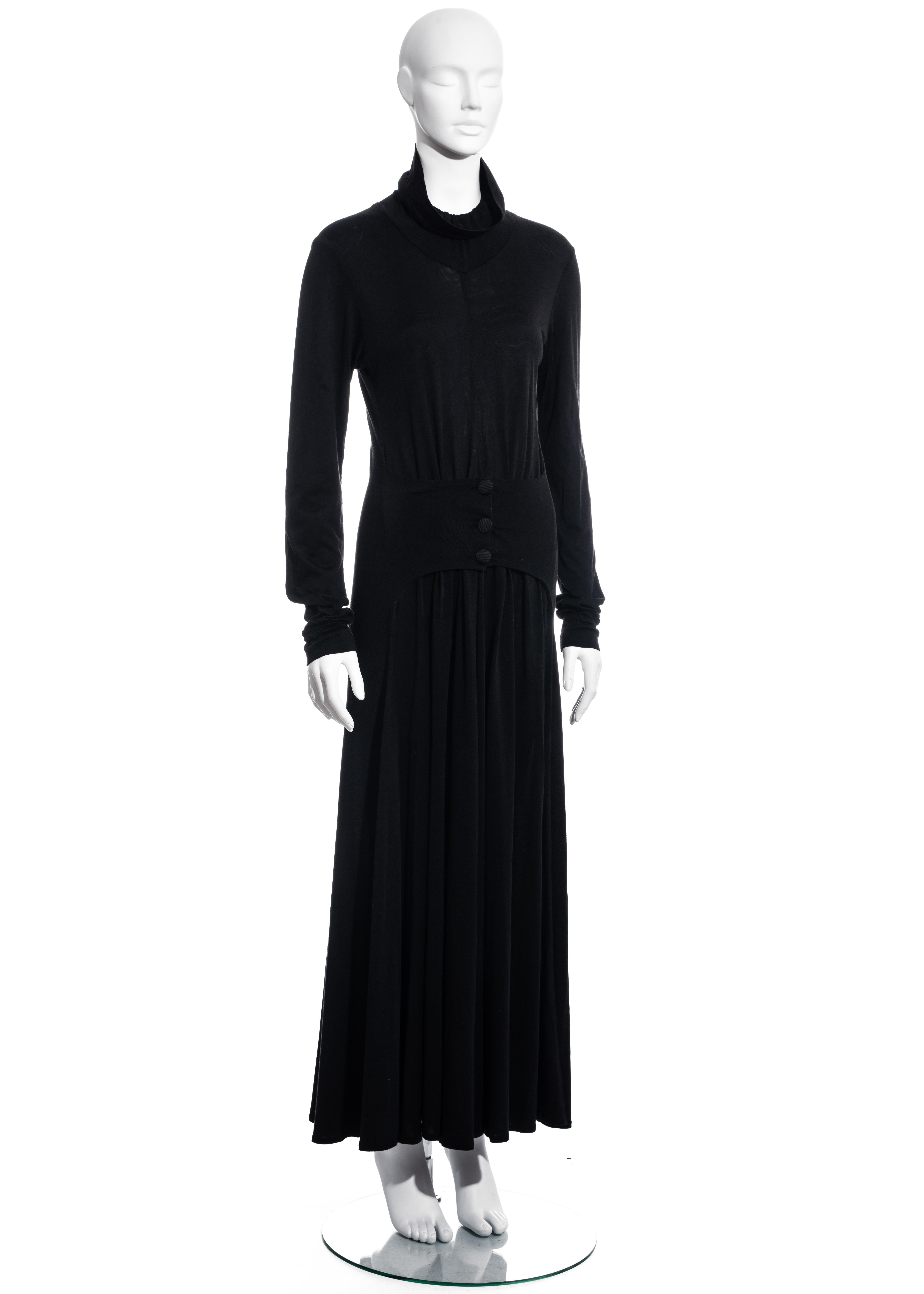 ▪ BodyMap black jersey maxi dress
▪ 52% Viscose, 48% Cotton
▪ Three front button fastenings belted at the hips 
▪ High neck with elastic collar 
▪ Size Medium
▪ c. 1980s
