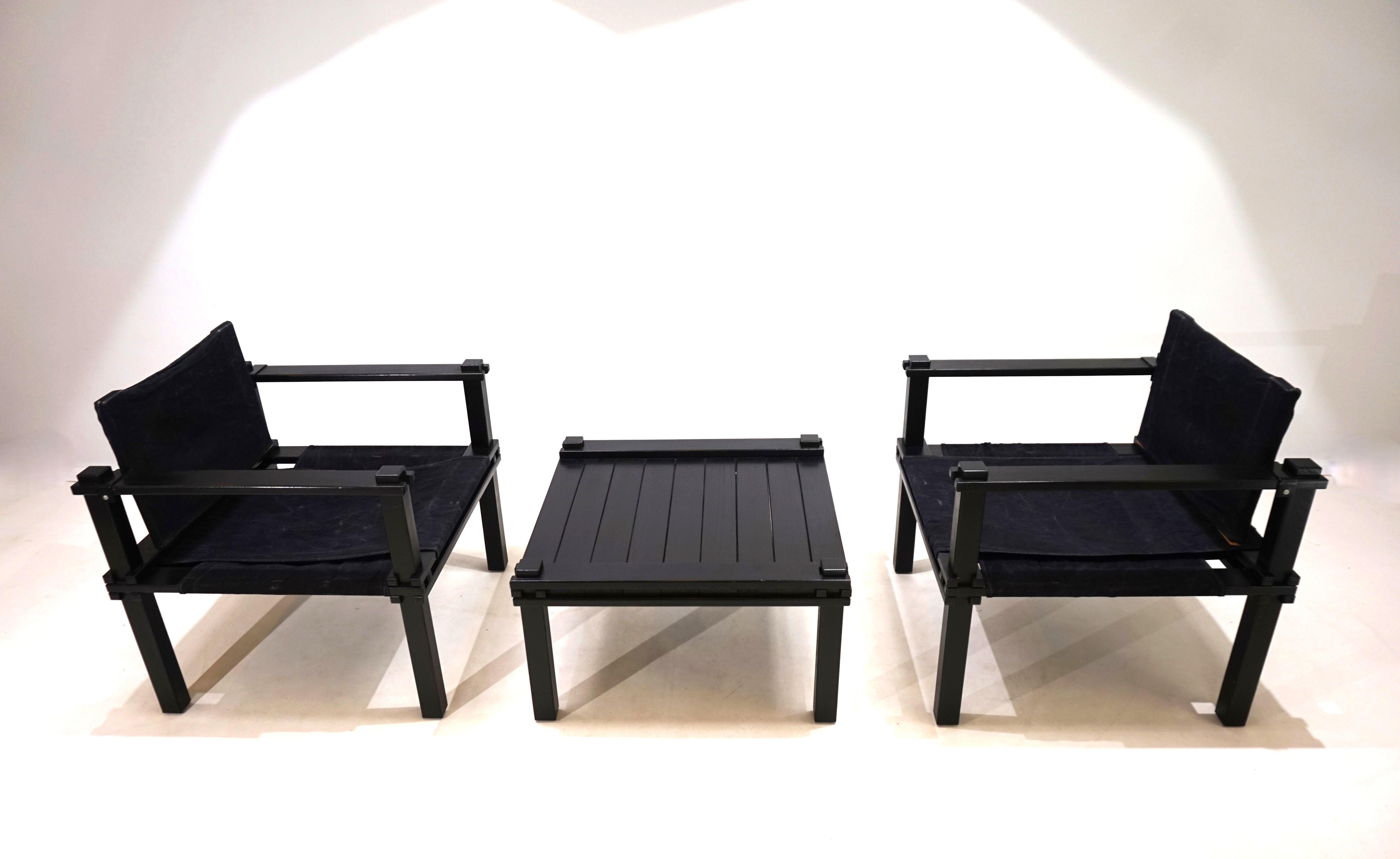 Les chaises de fermier noires et la table assortie sont en très bon état. Les lattes de bois présentent des signes d'usure minimes. L'assise et le dossier des chaises sont faits de toile noire qui a été tendue sur les lattes de bois et qui présente