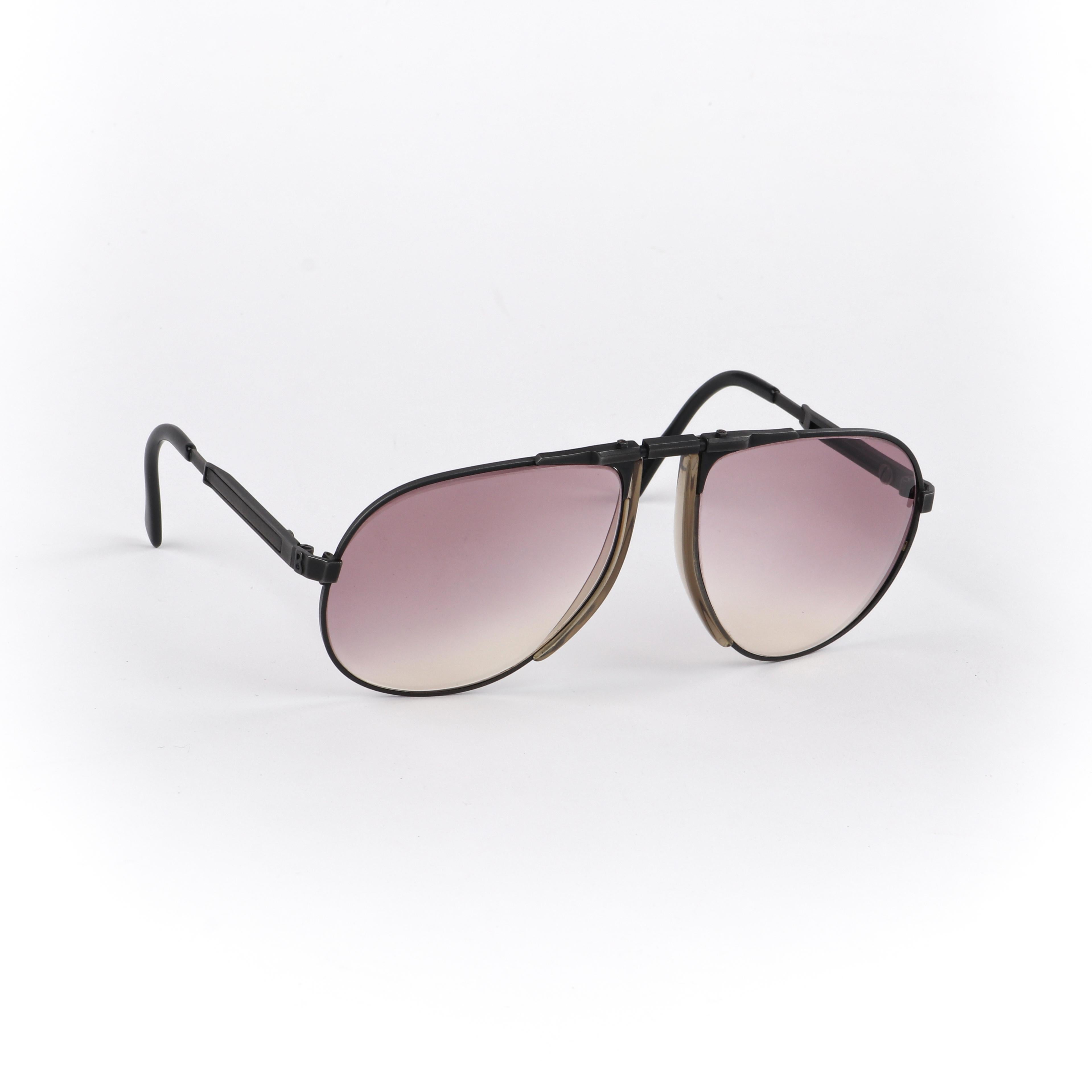 BOGNER c.1980’s Purple Tinted Adjustable 7001 Eschenbach Aviator Ski Sunglasses
 
Brand/Manufacturer: Bogner
Circa: 1980’s
Designer: 
Style: Aviator sunglasses
Color(s): Frame: black; lenses: purple
Lined: No
Unmarked Fabric Content (feel of):