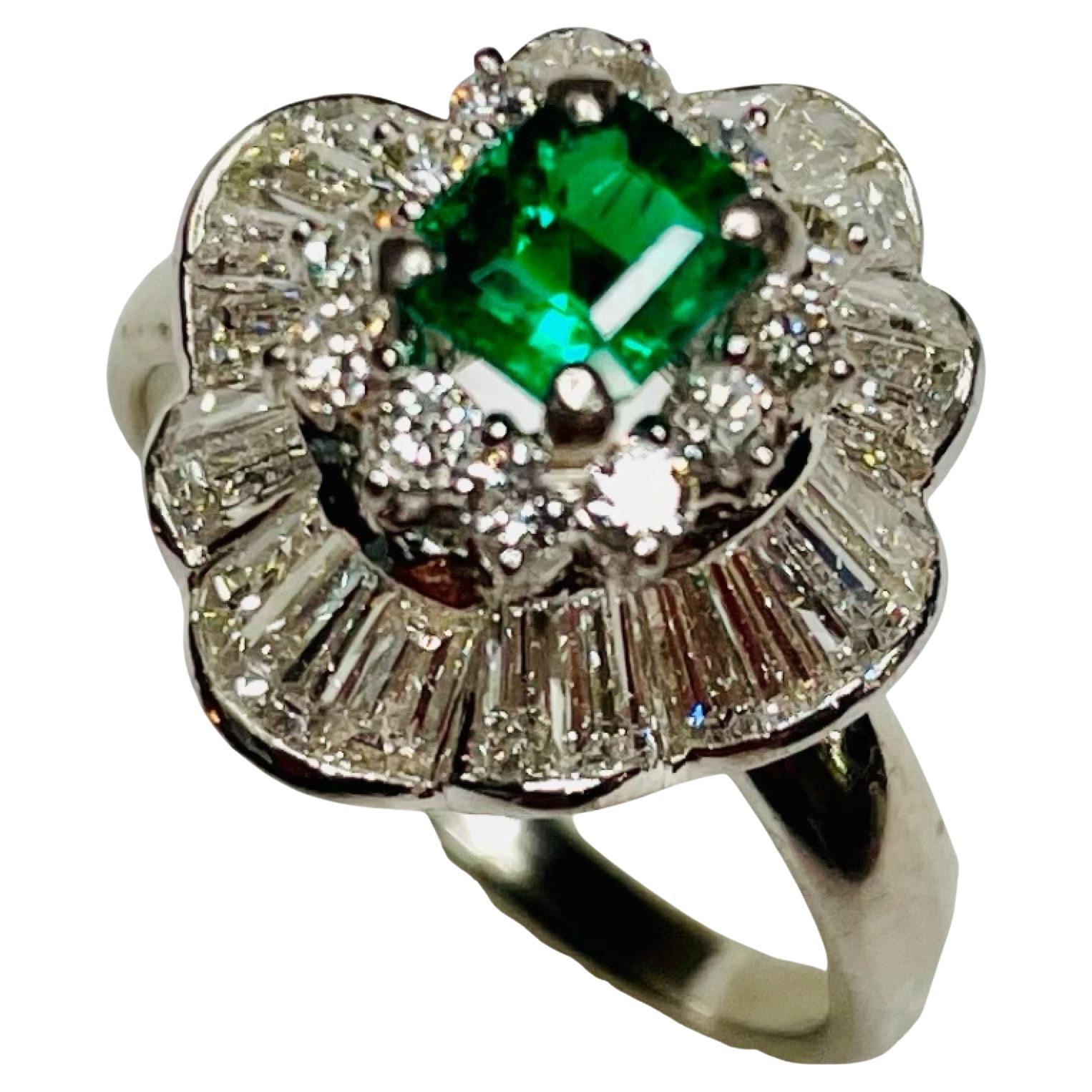 Bogo Platinum Diamond and Emerald Ring. This ring has 0.50 carat emerald cut emerald, set in four prongs in the center. This natural emerald is only oiled. It is VS clarity. There are 24 baguettes cut diamonds channel set in a wave pattern. There