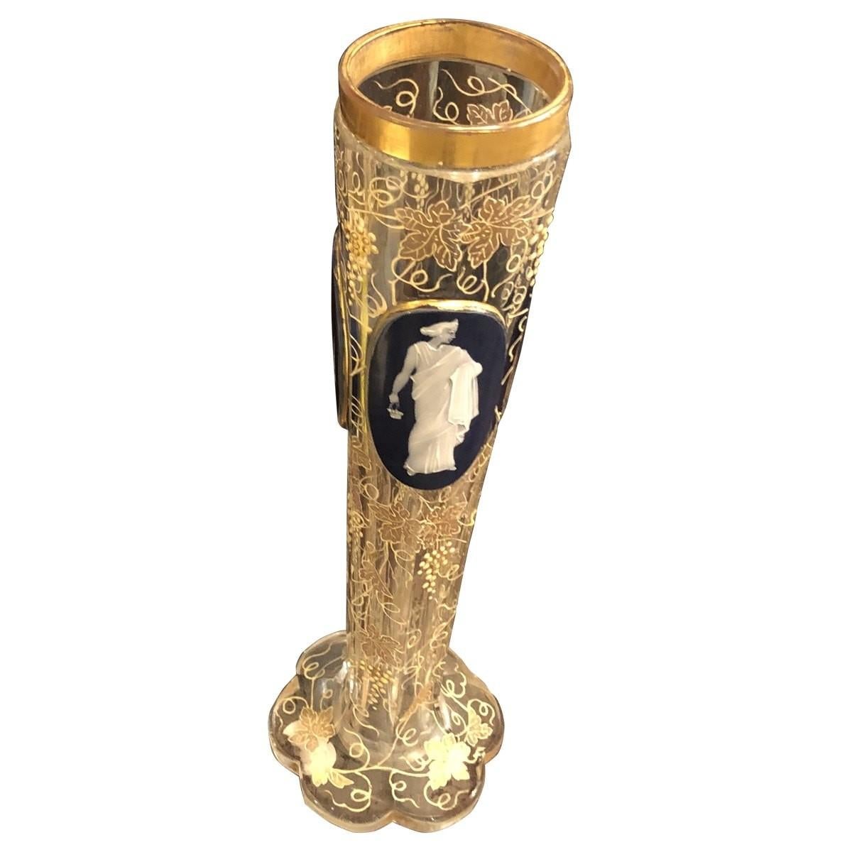 This cut and enameled vase is a stunning piece that is certain to capture your attention. The enameled vase is decorated all-over in the Moser style with scrolling grapevines. Each paneled side depicts a full-length cameo portrait of a maiden that