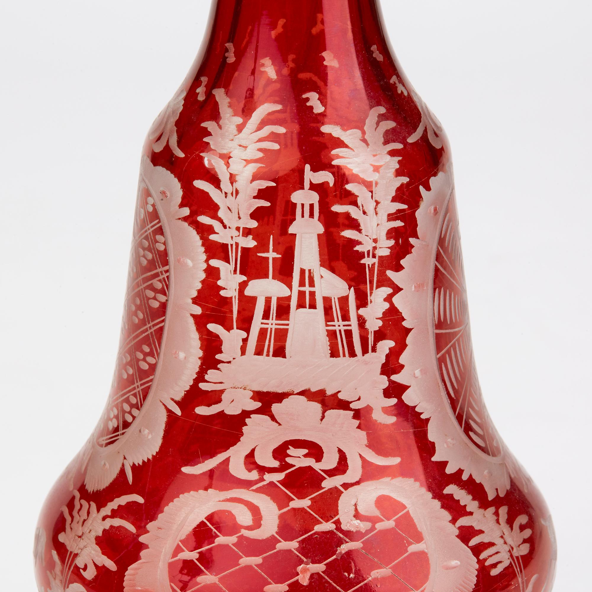 A fine pair antique Bohemian ruby flashed glass decanters and stoppers each engraved with a dog, running deer and various buildings set within landscapes and set amidst patterned designs with engraved scroll work around the foot. Both have original