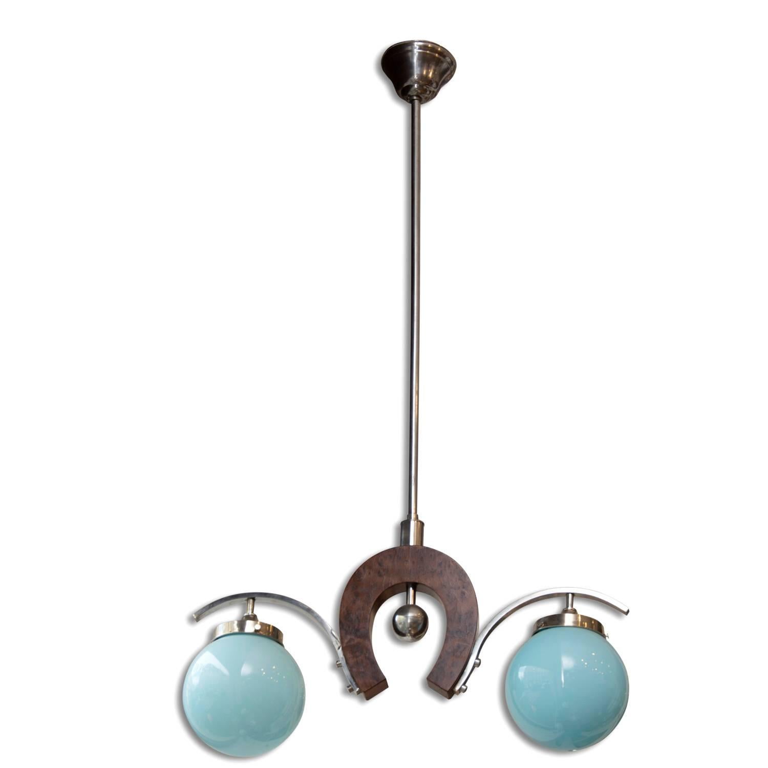 This Art Deco 1930s pendant light is in the form of the horseshoe and was made in the 1930s. The central globes in blue glass are connected by a wooden lacquered horseshoe suspended from a chrome rod. The pendant is in excellent condition.