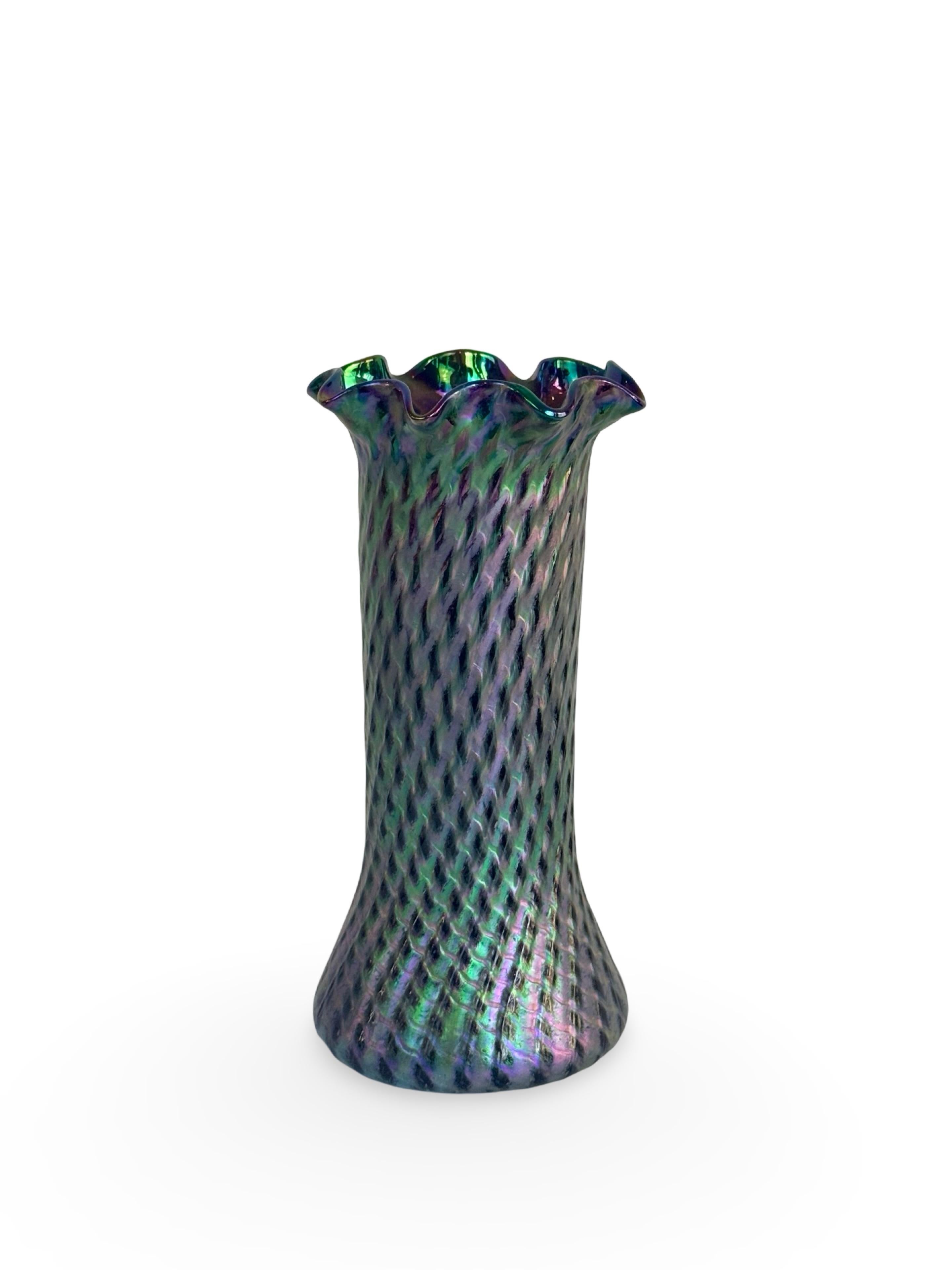 Vaso in vetro ametista del periodo Art Nouveau con iridescenze verdi e blu, un gioco di colori che prende vita attraverso la decorazione increspata che arricchisce il corpo e il bordo a balze. A seconda della luce e dell'ambiente circostante può