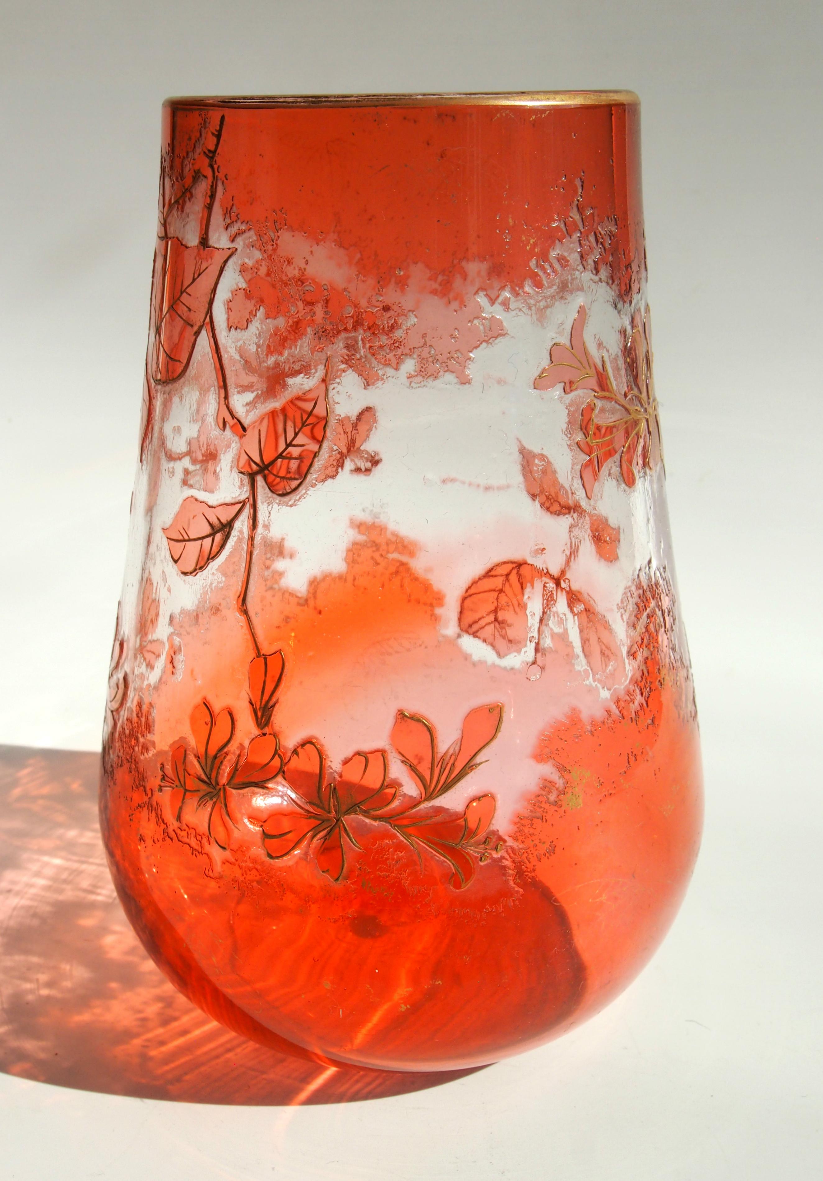 Un vase camée Harrach orange/rose sur fond clair de style Art Nouveau. Représentation de fleurs rehaussée de dorures. Ce style de camée a été présenté par Harrach à l'exposition de Paris en 1900. Leur technique de camée stylisée utilise un effet de