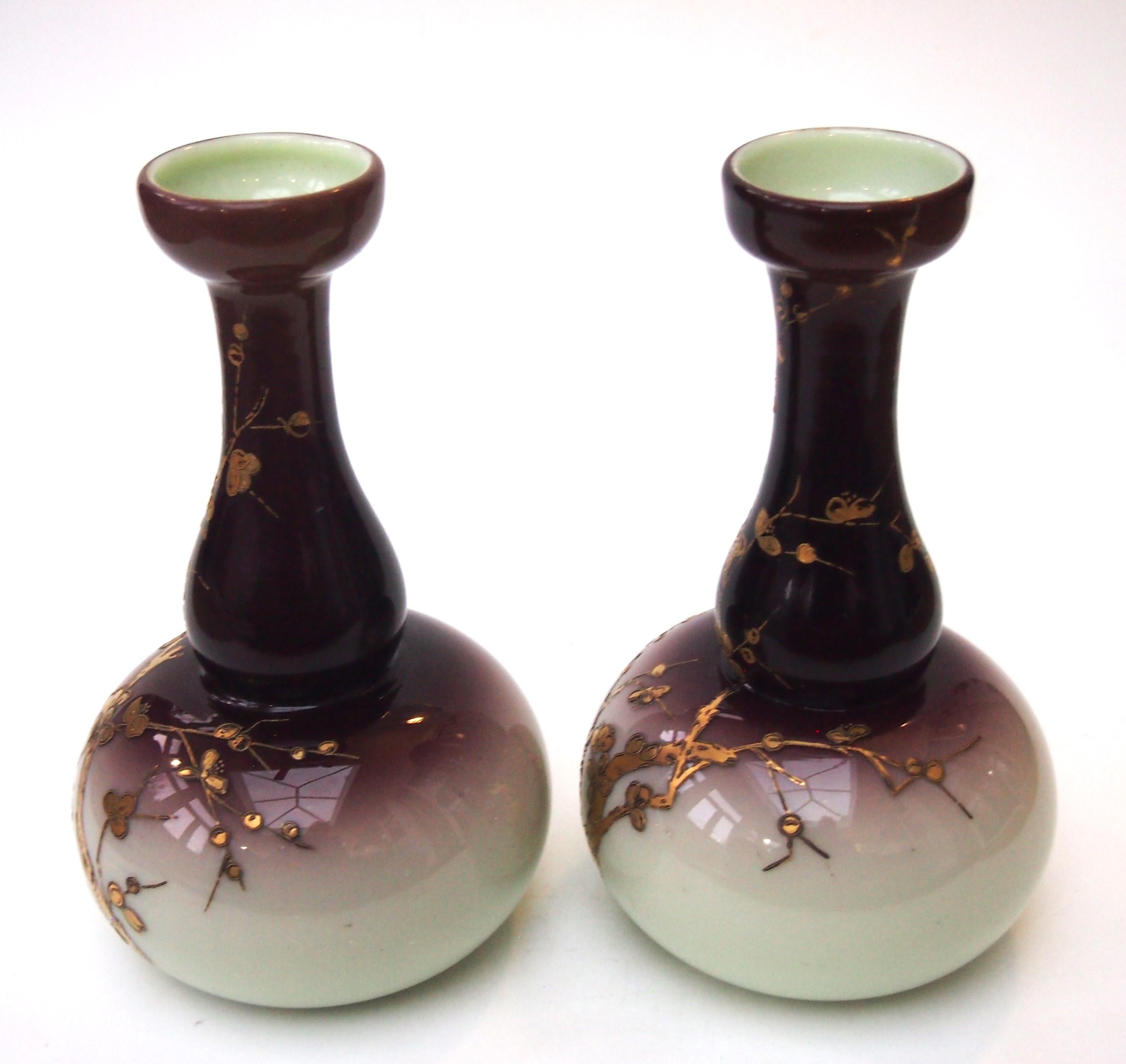 A vibrant Art Nouveau purple graduating to cream/ivory pair of deceptively heavy vases by Harrach decorated with raised gilding depicting blossoming branches - probably Prunus. Shaped in a barbers bottle form with slightly flared tops

 Harrach has