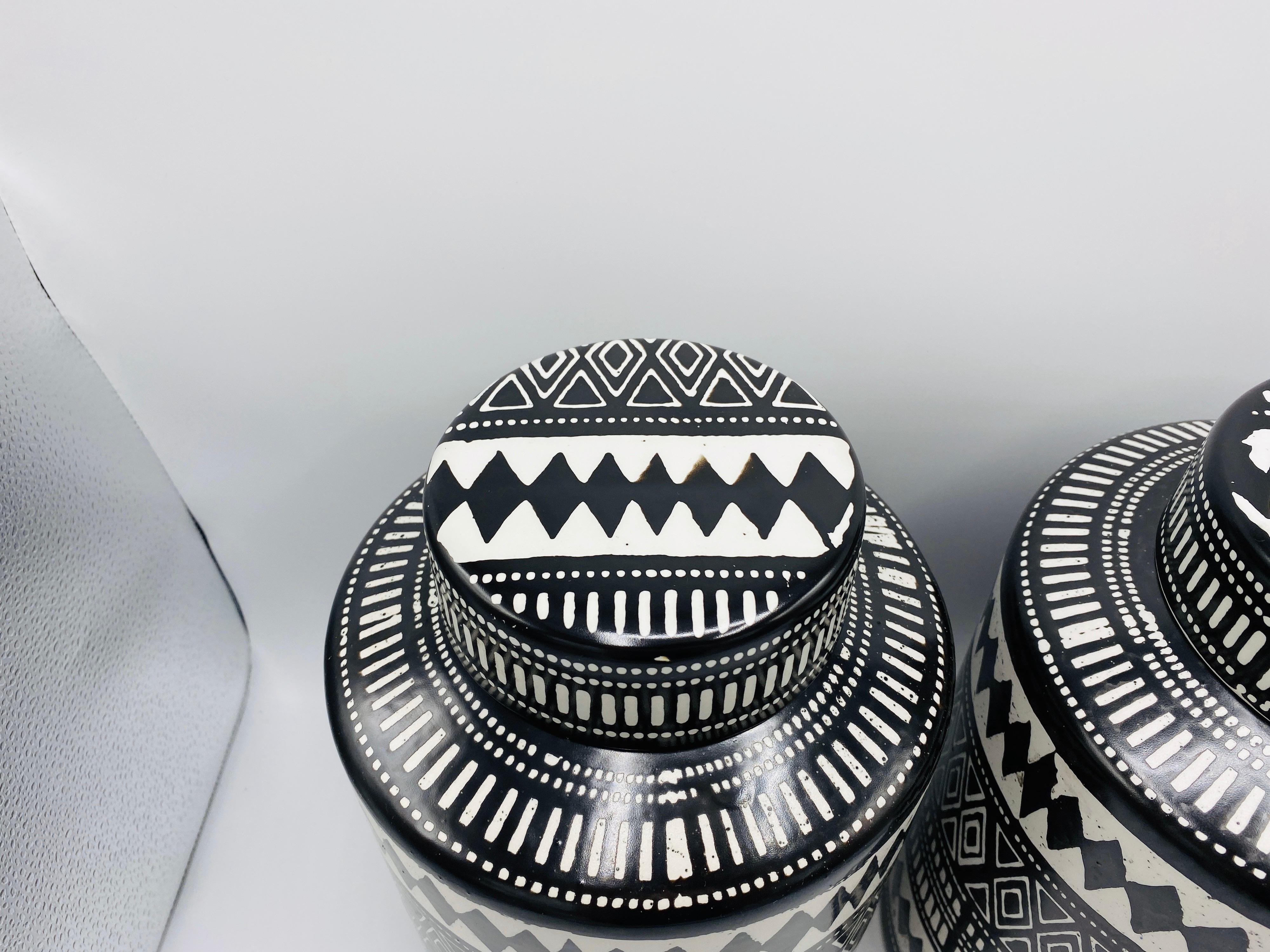 Listed is a striking pair of black and white ceramic transferware, African/Aboriginal Bohemian style ginger jar canisters with lids. New; maker unknown. Each measures: 12.5