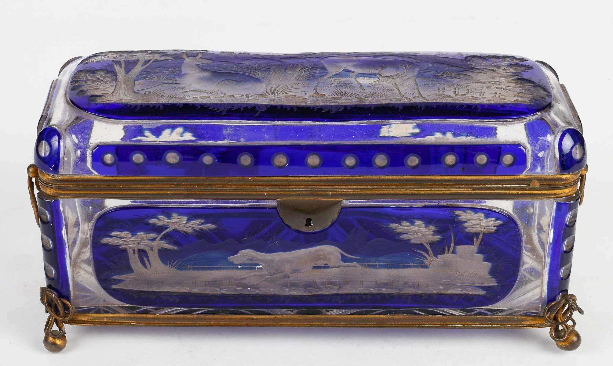 Bohemian crystal box, 19th century, Napoleon III period.

Bohemian crystal box, brass mounting, engraved hunting scene, 19th century, Napoleon III period.    
h: 13cm , w: 25cm, d: 10cm