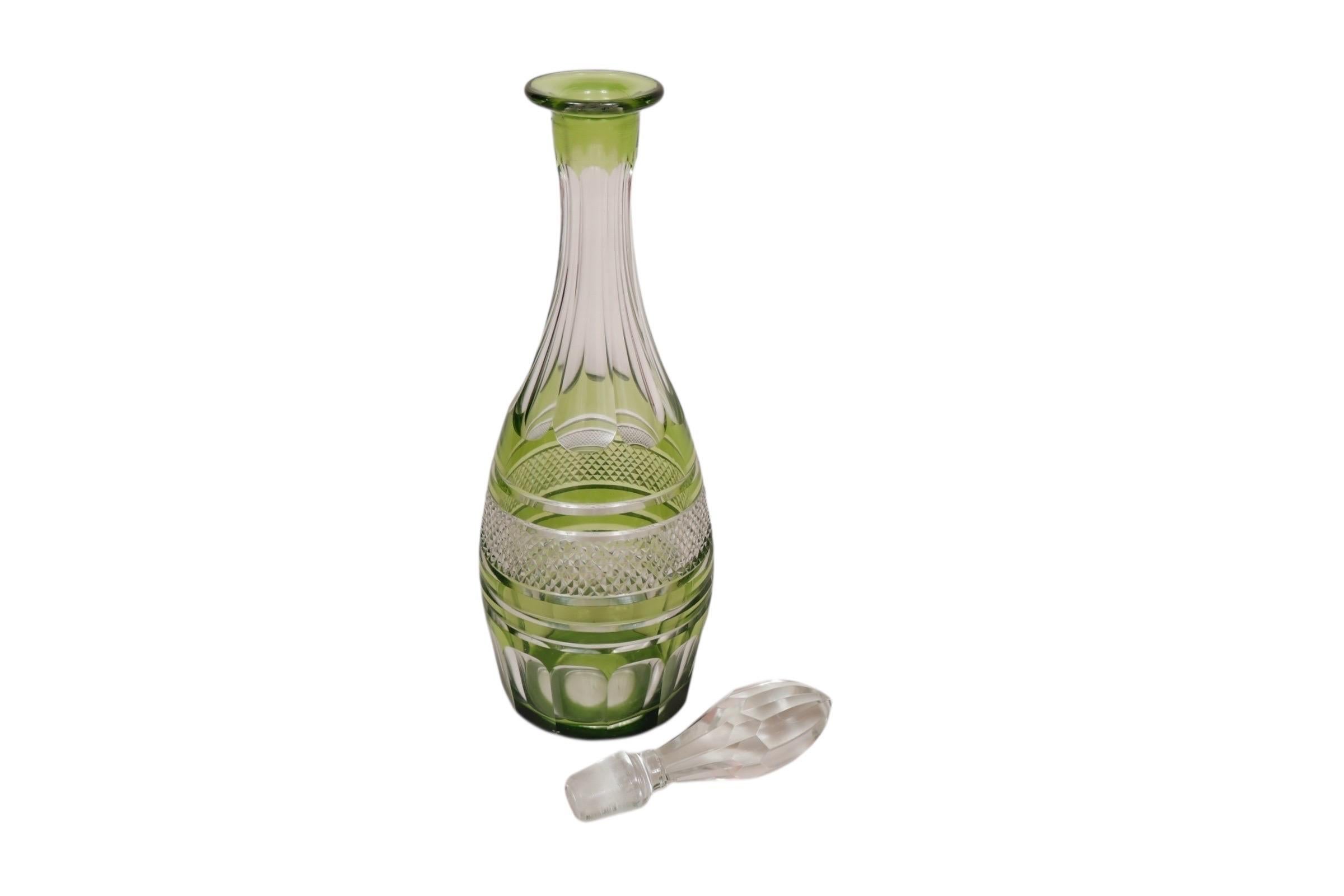 A Bohemian cut glass decanter in olive green. Decorated with a diamond cut band framed with beveled lines, and fluting on the neck and around the base.