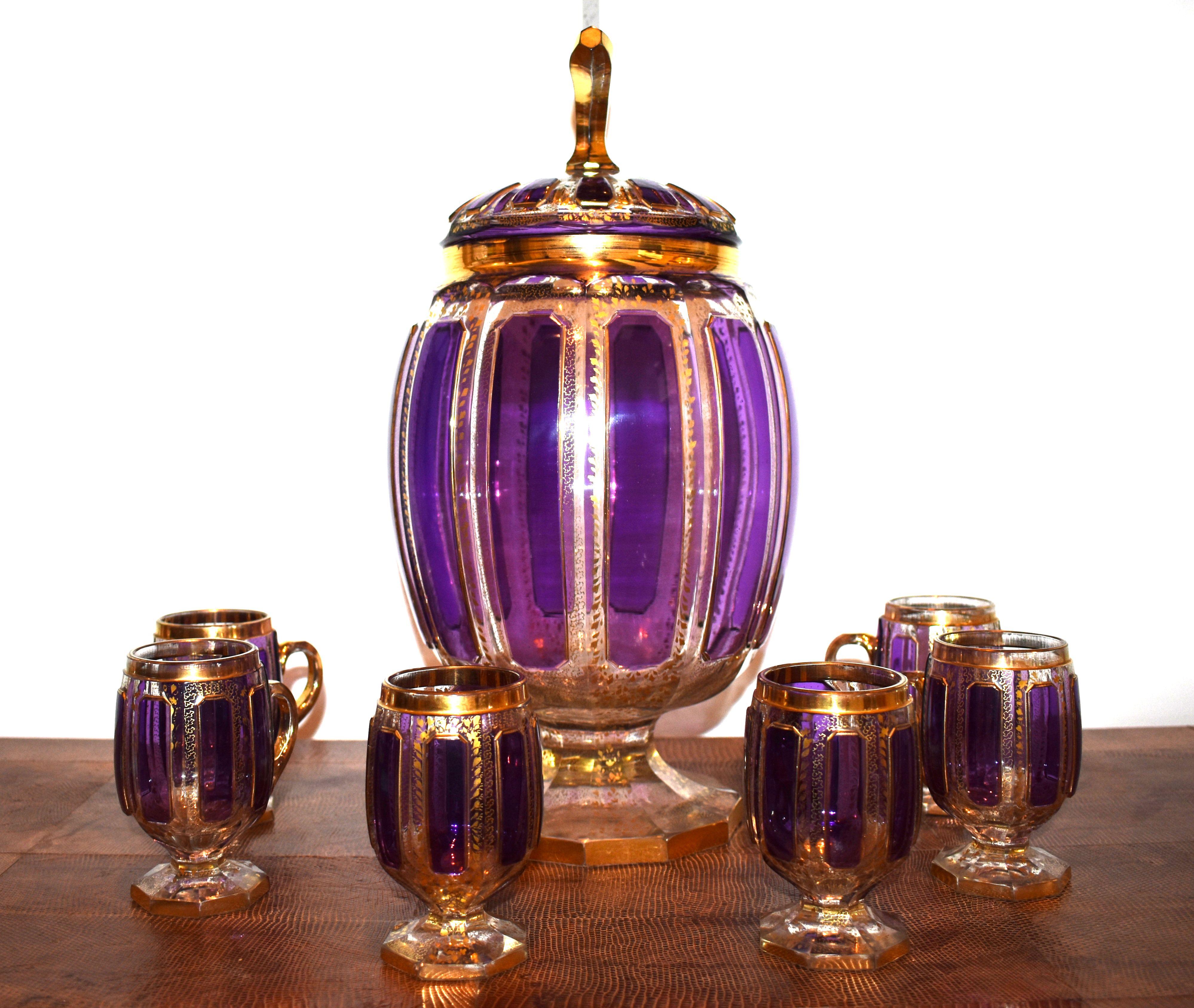 Set di bicchieri in cristallo soffiato a mano di Boemia. Sei tagli con una grande brocca dorata in oro, viola e cristallo trasparente.

Dimensioni:
Brocca 16 pollici H. per 8 pollici Dia.

La tazza misura 4,25 pollici di H. per 4 pollici di L,