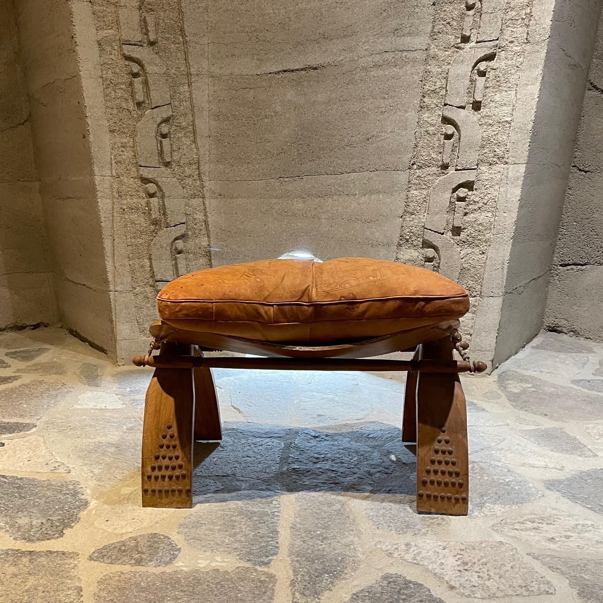 Vintage Egyptian Camel Stool Wood with Raw Hide Rope Ties. Leather on Stool with Embossed Drawings unclear. Gold trim accents.
18h 27w x 14w inches
Unrestored Preowned Vintage Condition. Original leather cushion filled with horsehair.
Scratches on