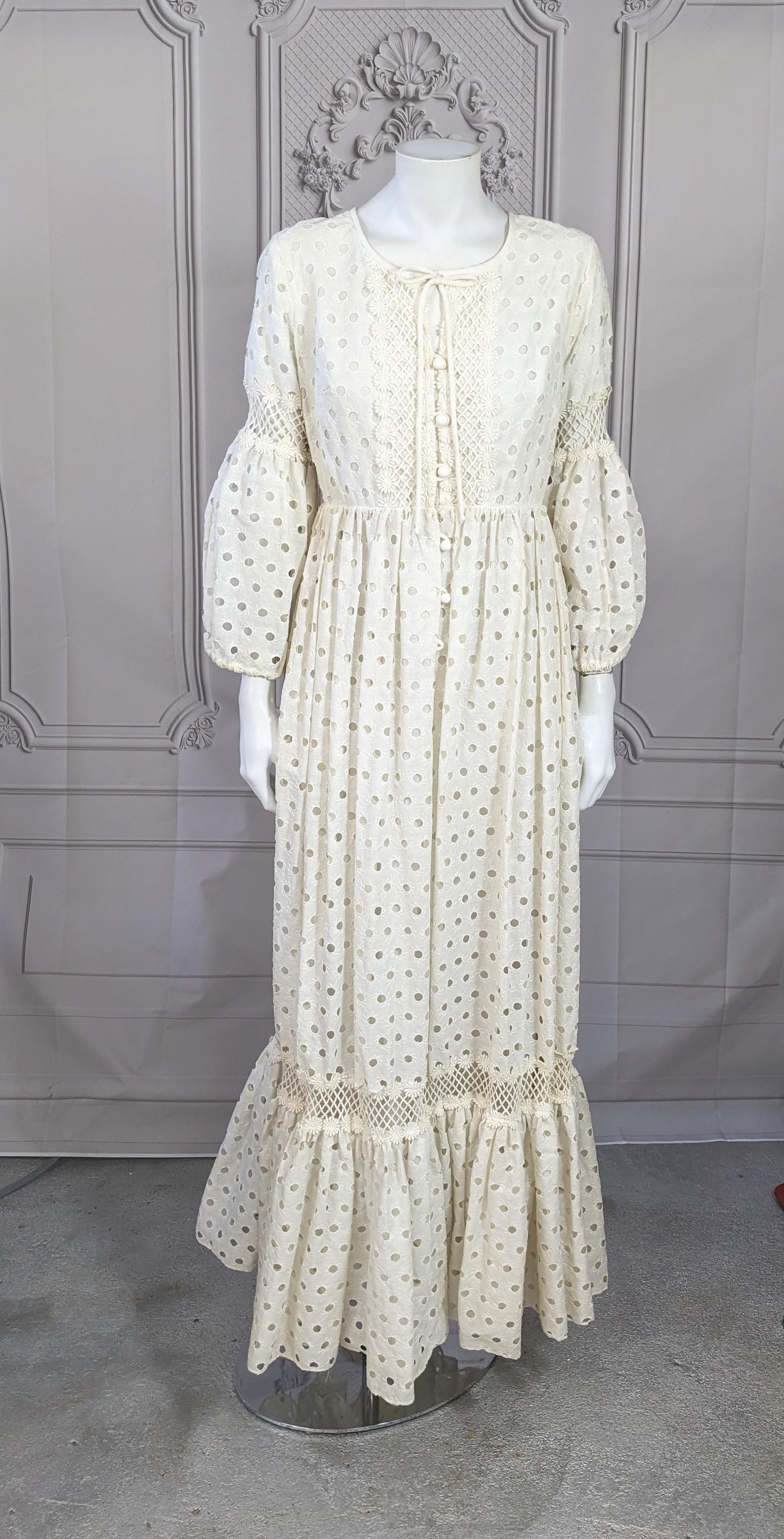Charming Bohemian Lace Maxi Dress from the 1970's. Crisp cotton eyelet with high waist and dropped puffed sleeves. Gathered full skirt falls from waist with large ruffled hem. 
Filet see through lace strip at the top of each ruffle, with the rest of