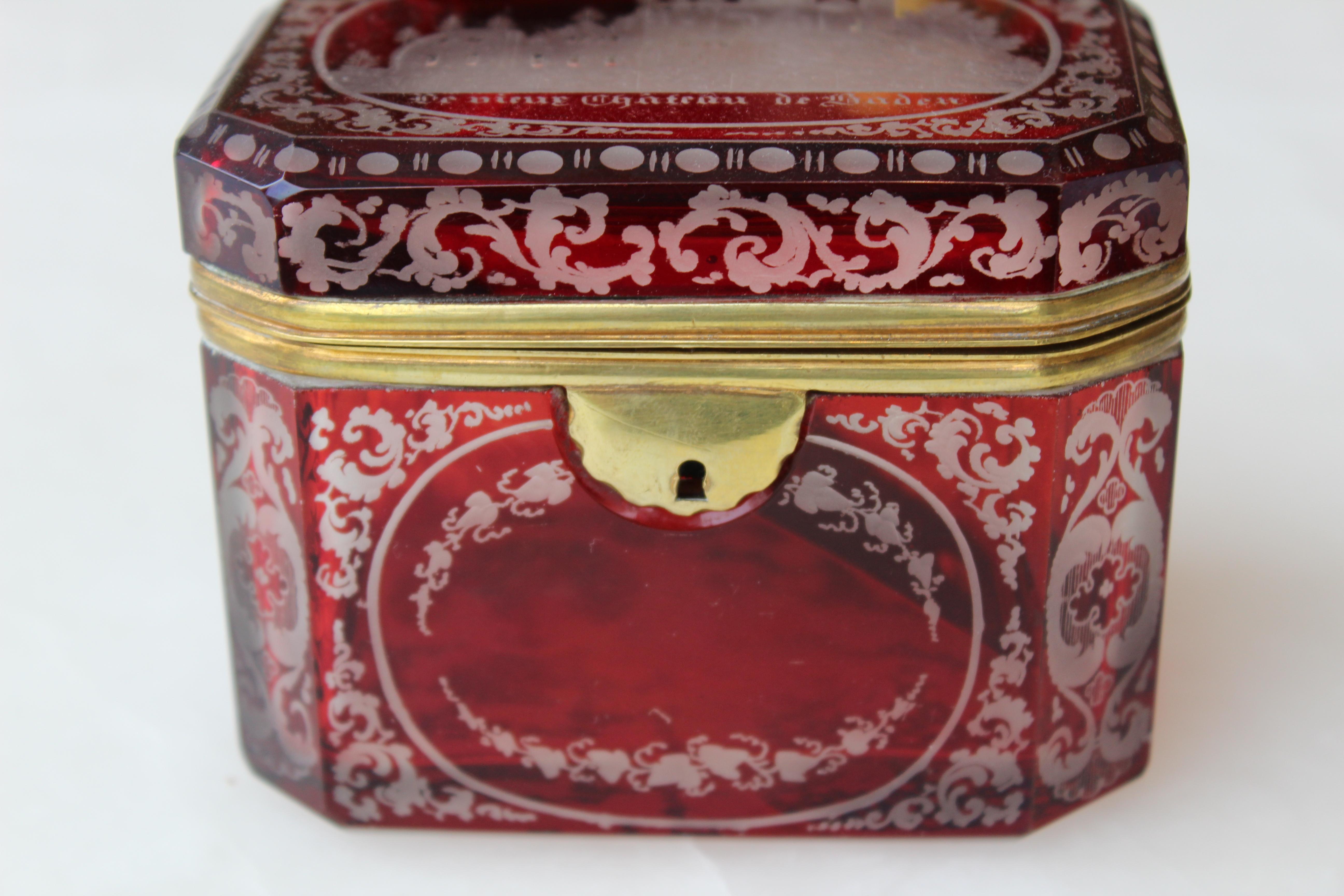 A rectangular flash cut souvenir casket in ruby red, with gilt bronze mount and escutcheon (no key), circa 1880
The cut to clear motifs depicting picturesque views of the German city of Baden-Baden. The lid is decorated with a panoramic view of the
