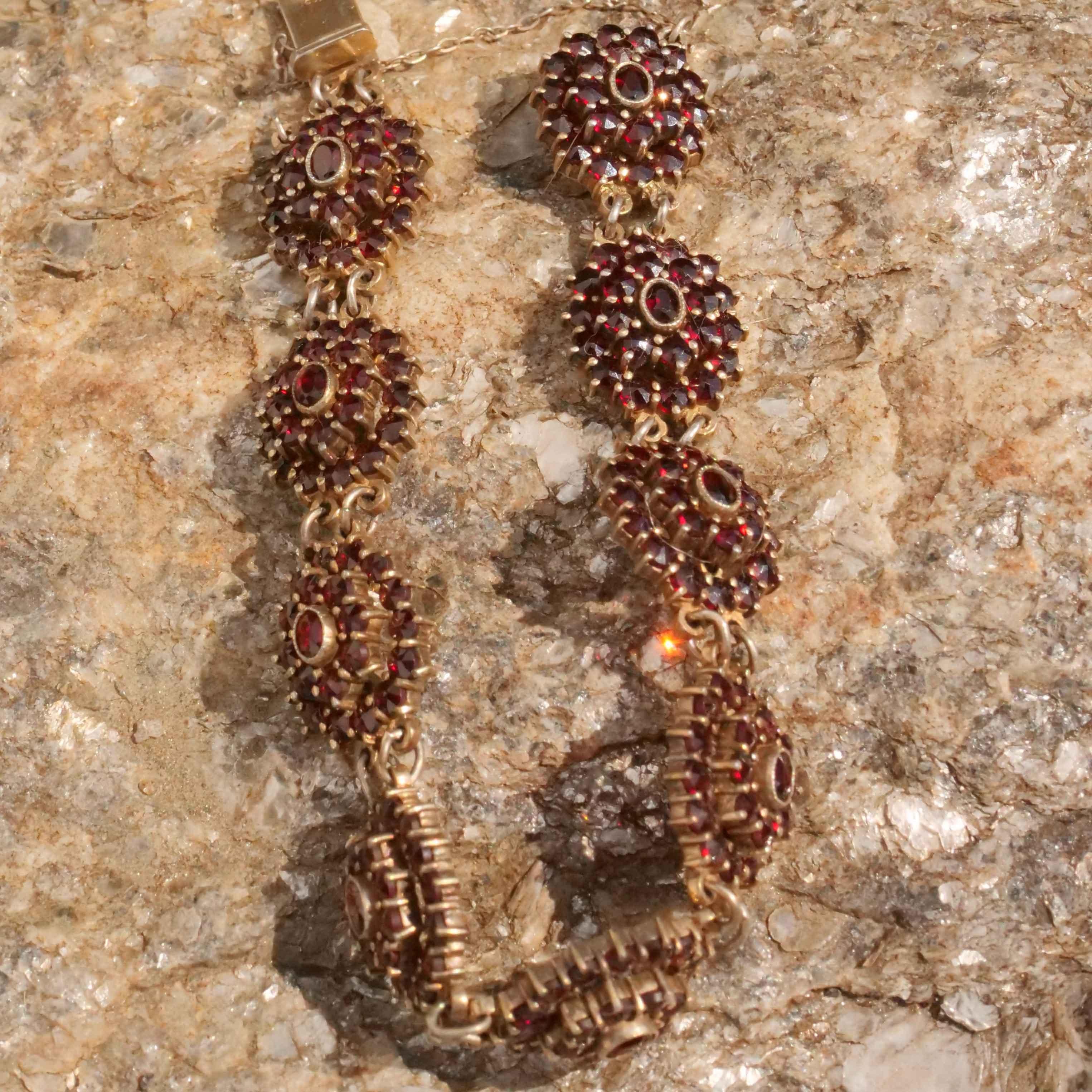 This fine bracelet was made in Bohemia circa 1910. The design consists of nine round links set with numerous bright faceted garnets which are hinged together. The garnets are bead set and there is mil grain finishing around the larger central