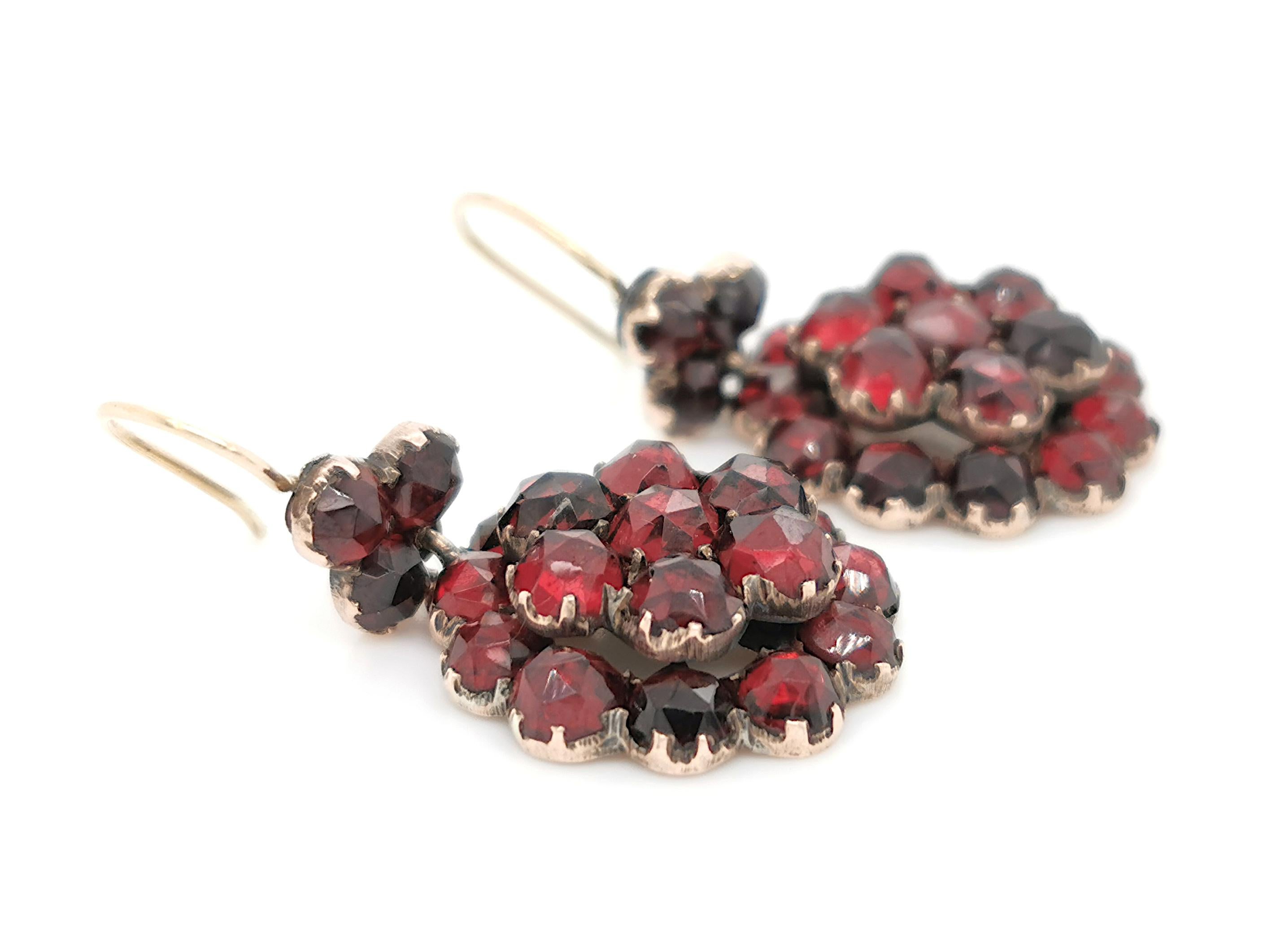 A pair of Bohemian garnet earrings, consisting of a circular cluster of rose cut garnets, suspended from a further trefoil of rose cut garnets, in closed back settings, mounted in silver-gilt, with gold French wire fittings, circa 1880.