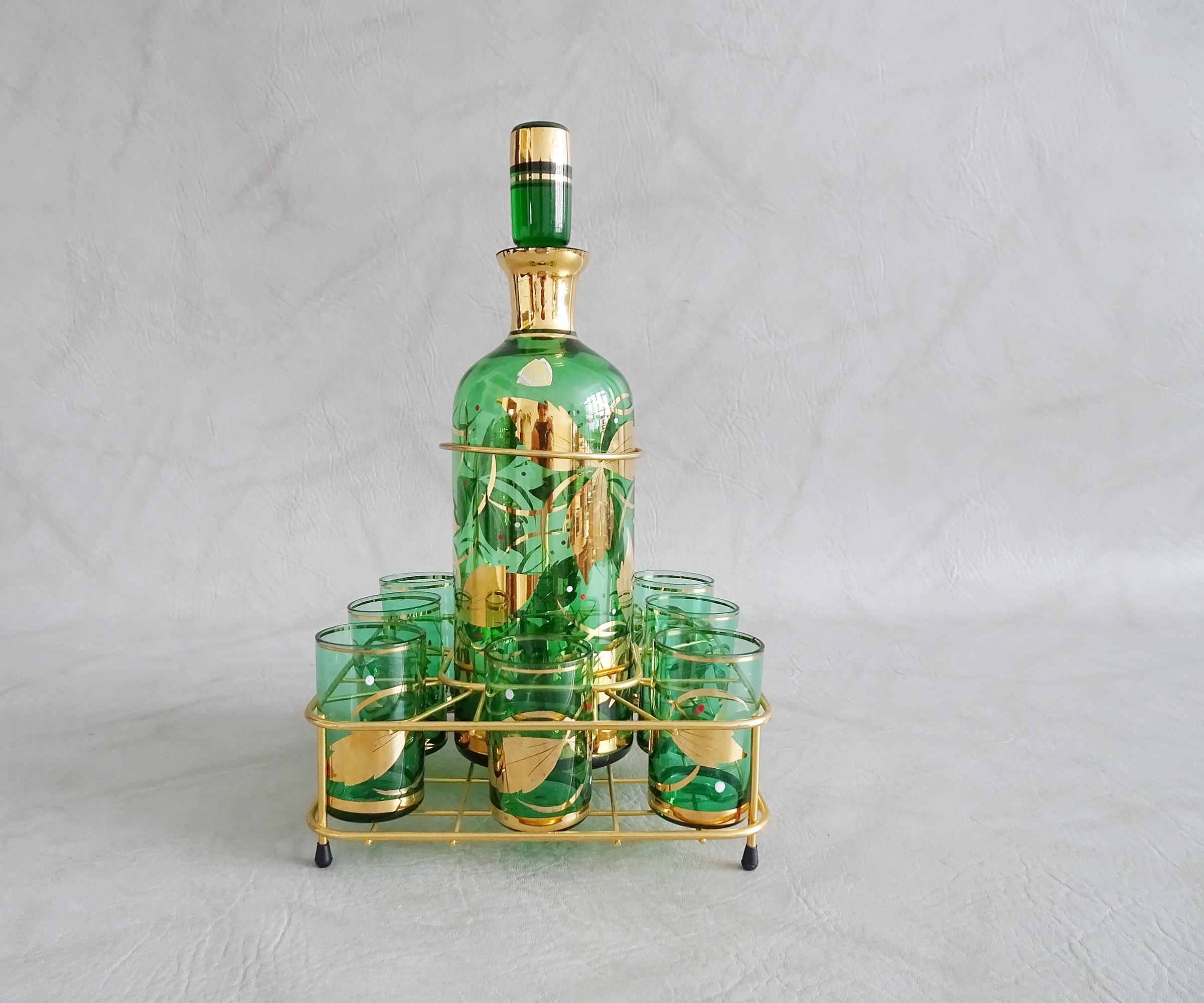 Genuine Bohemian glasses set with a decanter in a gold-colored stand. A stylish mid-century Czech glass art piece. Green glass with golden foliage and small enameled dots in white and red.

A fancy bar accessory consisting of eight glasses and a