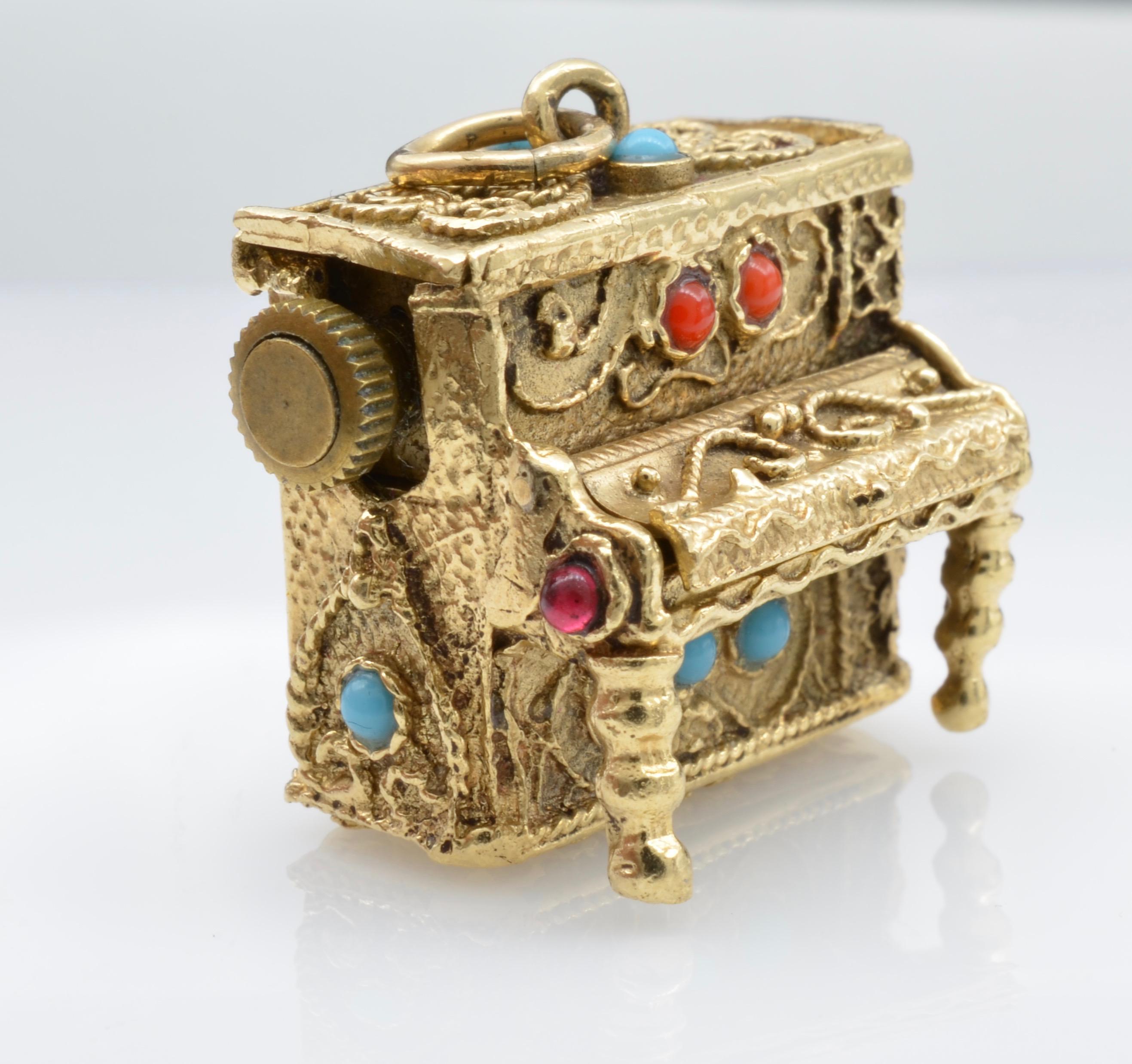 This Bohemian Piano Music Box Pendant is ornately decorated with colored glass in shades of Turquoise, Coral, and Ruby. Spiral intricacies like wavering vines detail this exquisite vintage pendant cast in 18K yellow gold. Elaborate and beautiful