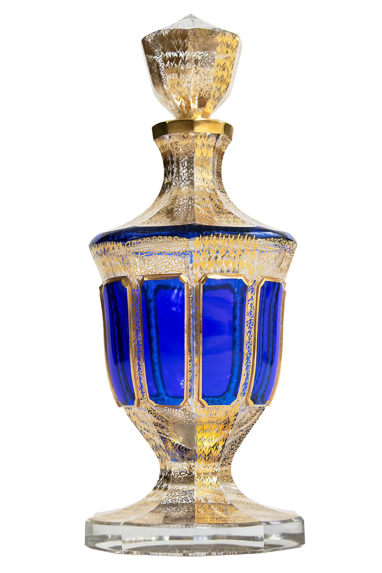 Bohemian handmade color glass with gilded decor carafe.
This carafe is made of thick and heavy glass that is transparent and decorated with blue color glass, gold pattern through the glass.
Very good condition.
 
  