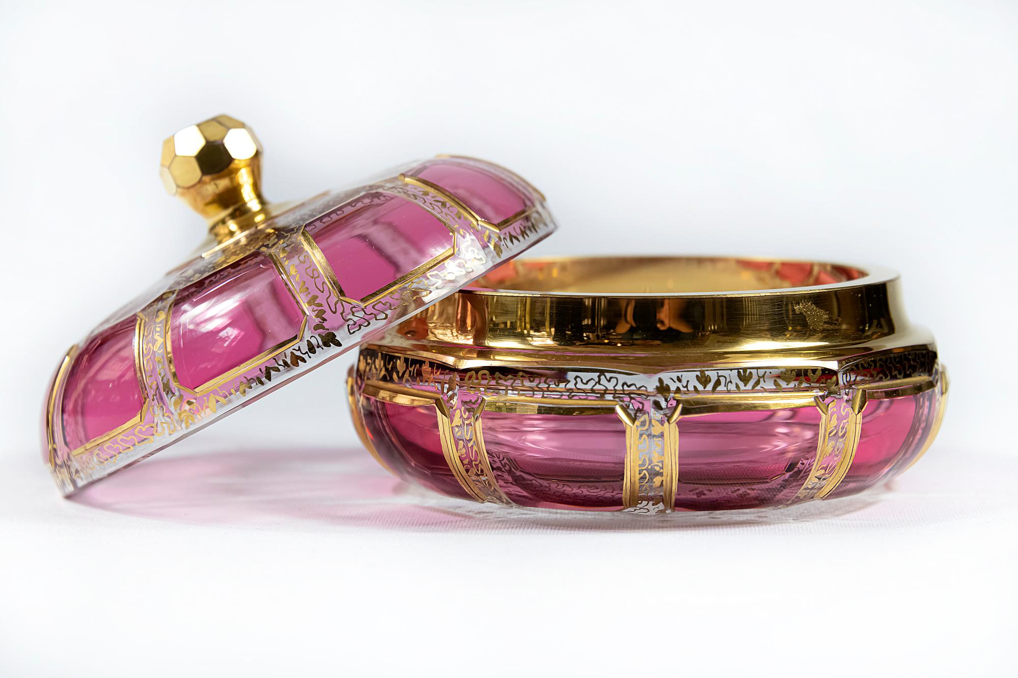 Bohemian glass box with lid and gilt surface. 
Transparent glass decorated with raspberry colour glass, gilt trims and gold pattern through the glass.