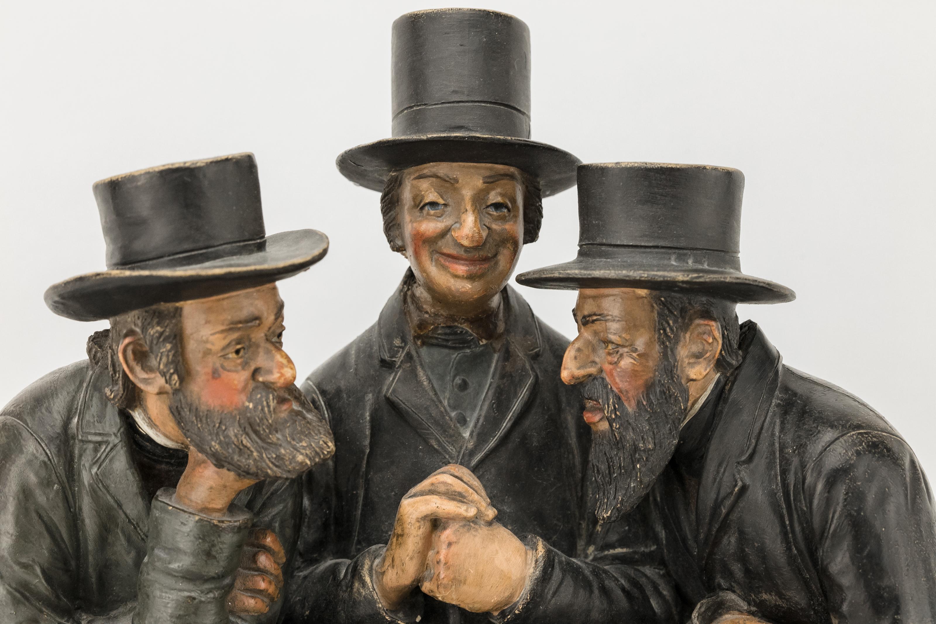 Painted earthenware figure group of three Jews in overcoats and skullcaps, sitting close together on a bench. Their detailed faces have stereotypical Jewish features, such as sidelocks and large, protruding noses, circa 1900, Bohemia.
Unlike