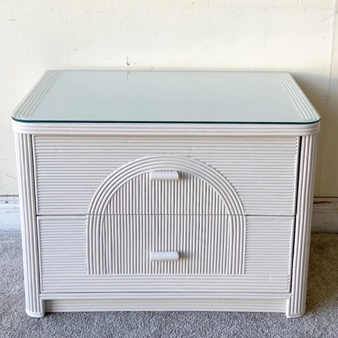 Exceptional boho chic white pencil reed nightstand/end table. Features a glass top with an arched pencil reed design across the two spacious drawers. 