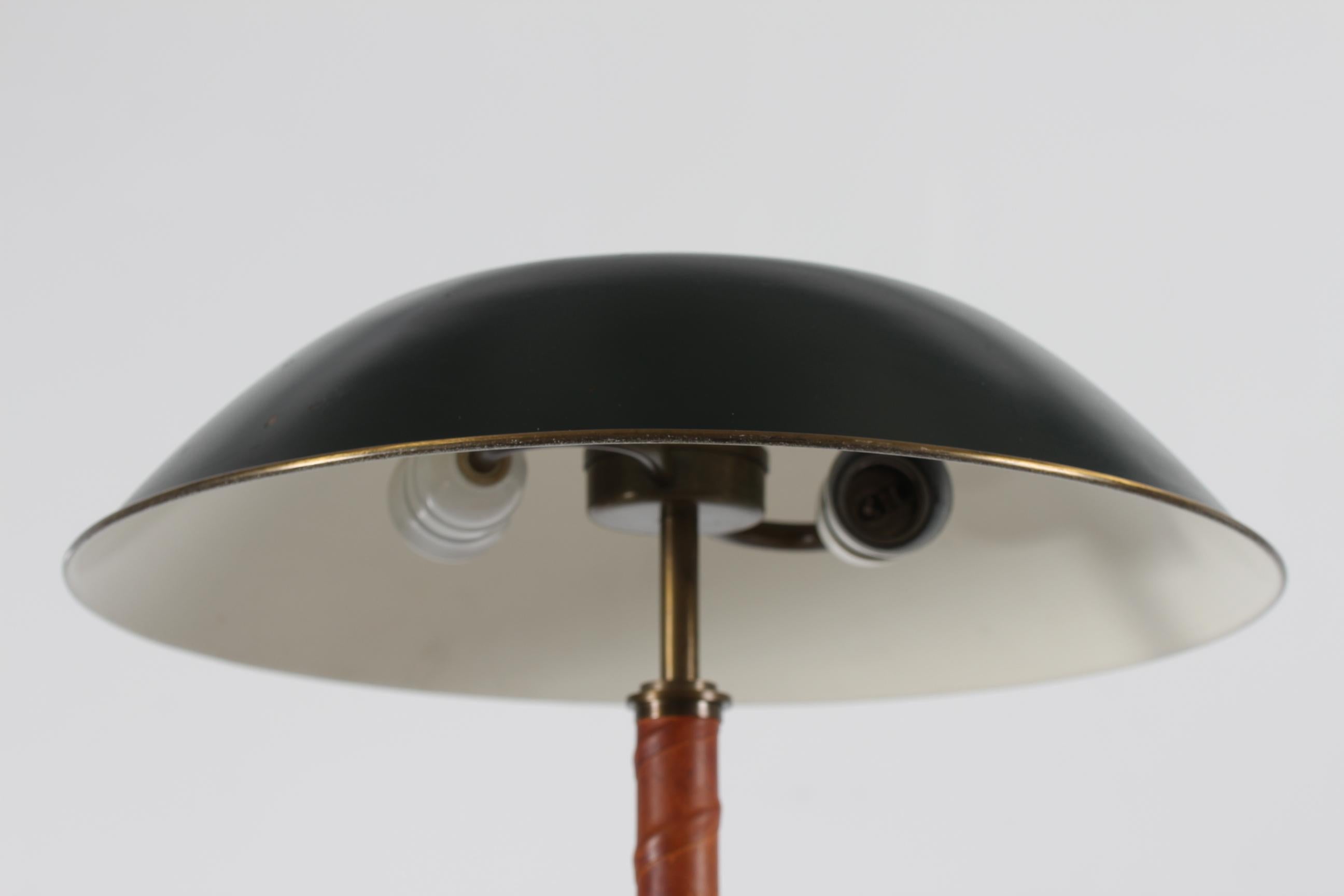Vintage Swedish table and desk lamp designed for Bohlmarks in circa 1940 for Nordiska Kompaniet, Stockholm.

The table lamp is made of brass, the stem winded with patinated natural leather. The shade is made of metal with dark green